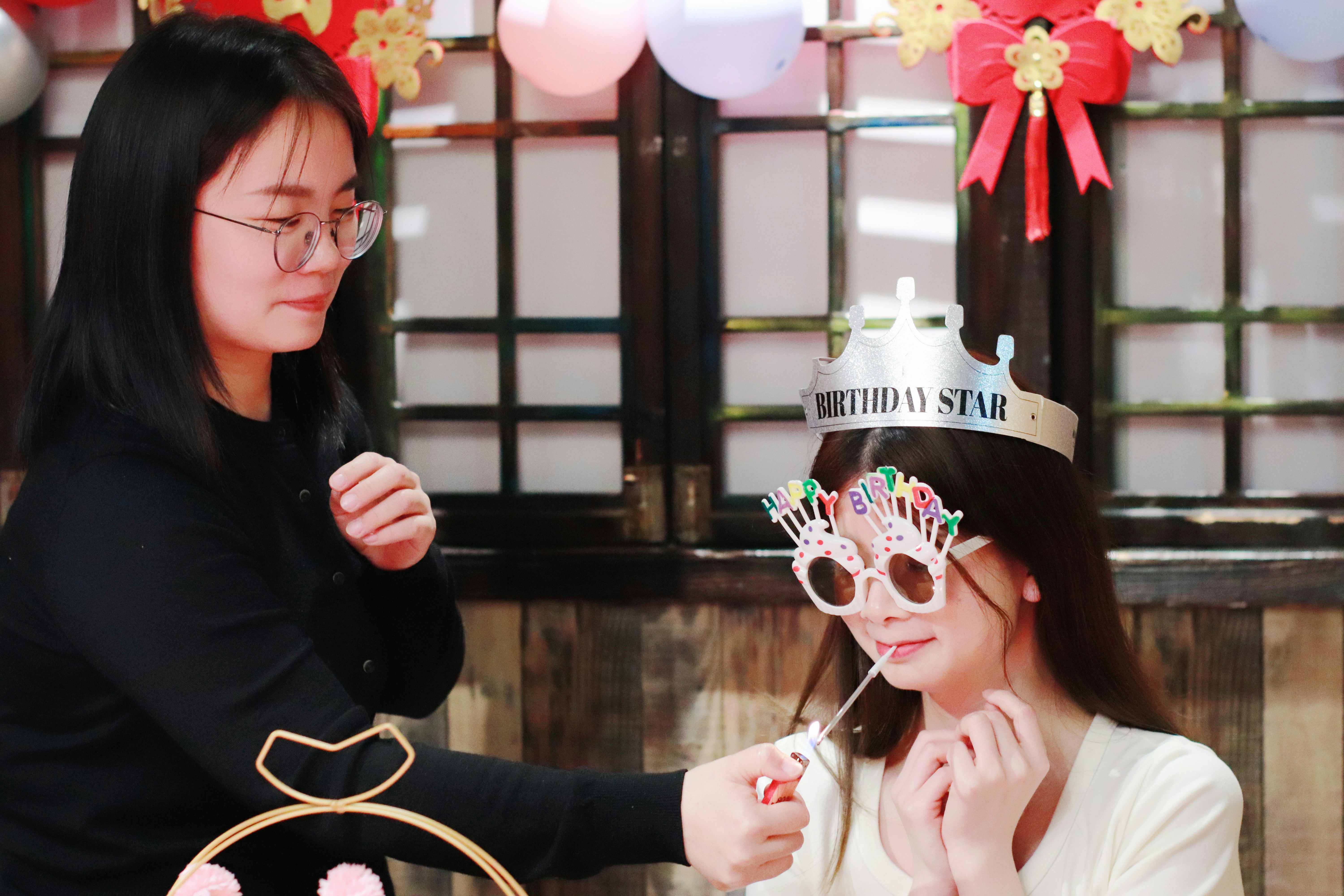 Woman lights candles on birthday crown for friend.