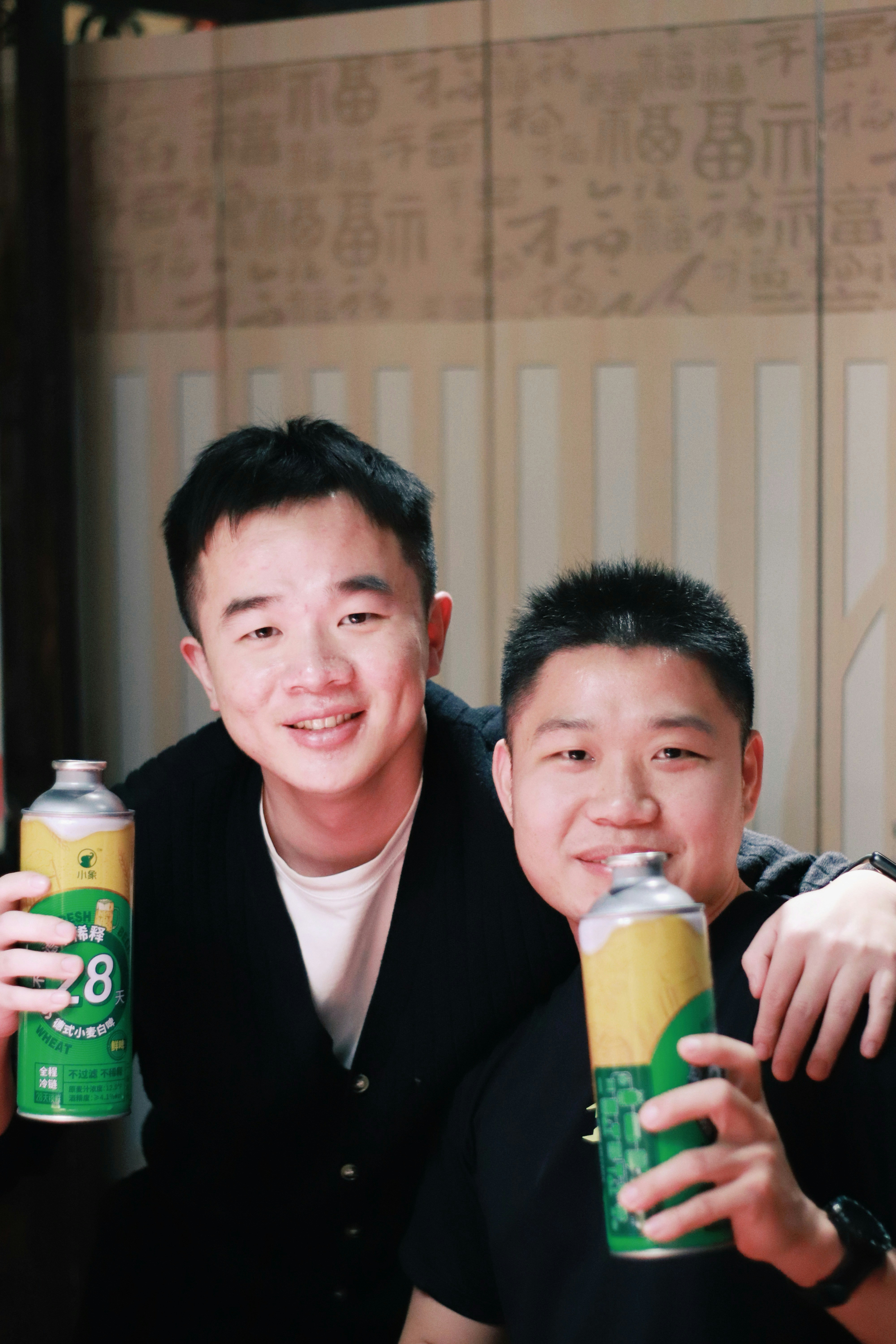 Two smiling men holding cans of beer