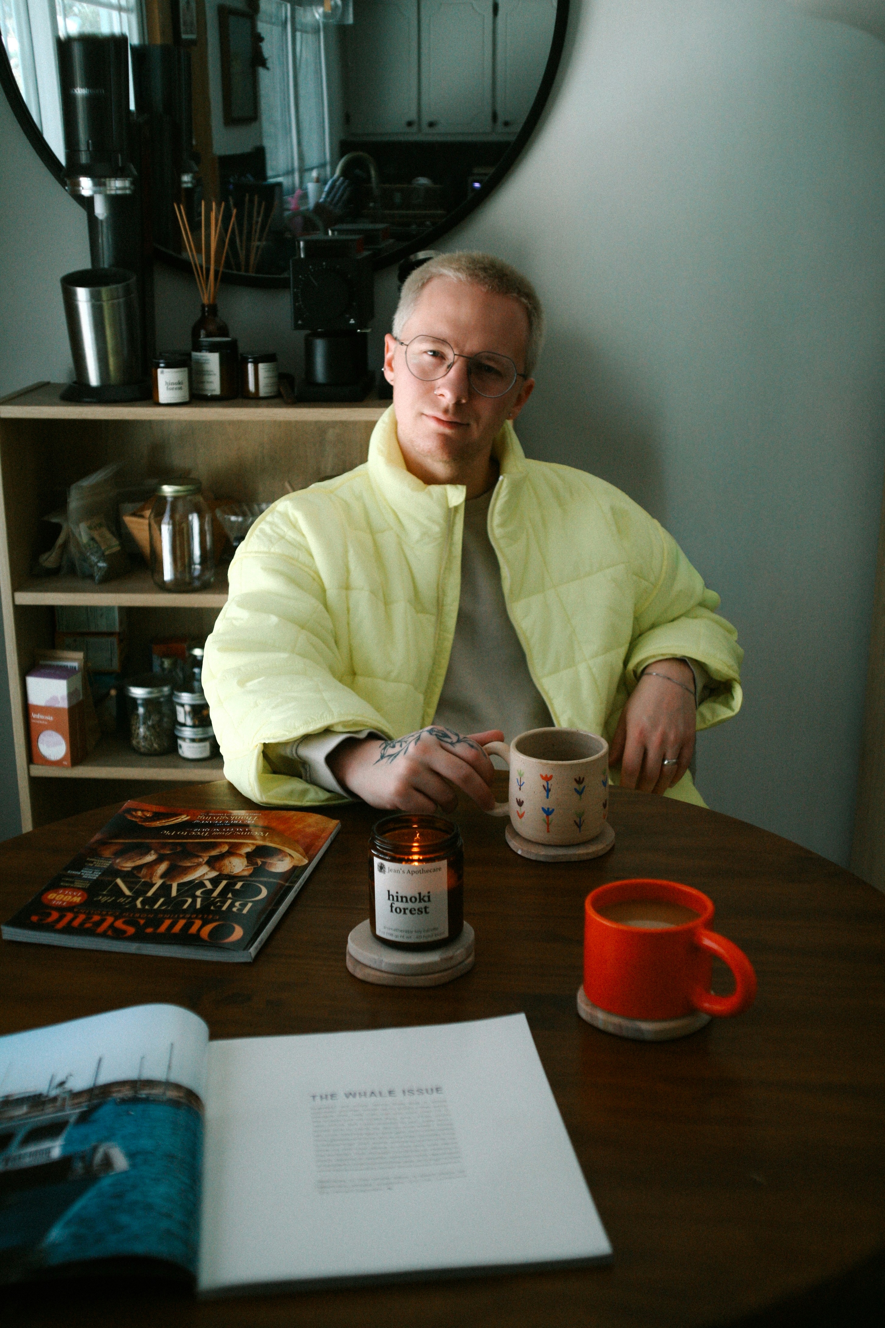 Uomo con la giacca gialla che tiene una tazza di caffè al tavolo