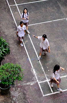 Four students in school uniforms on a court.