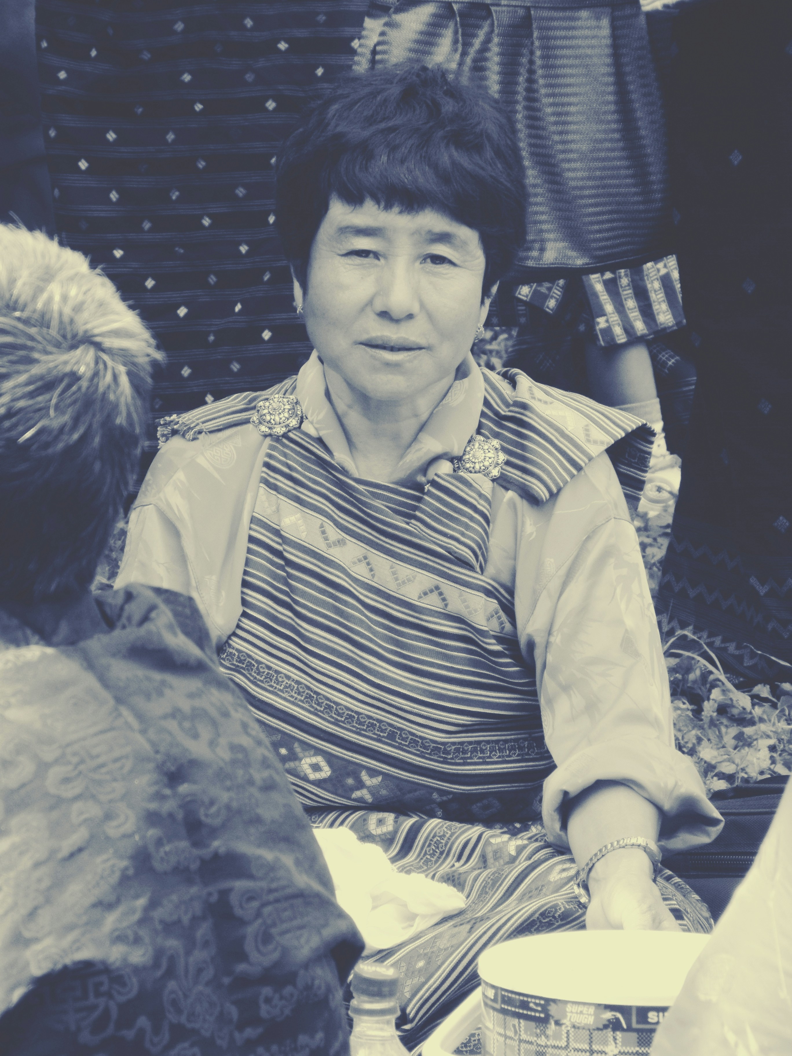 Elderly woman in traditional clothing smiles at the camera.