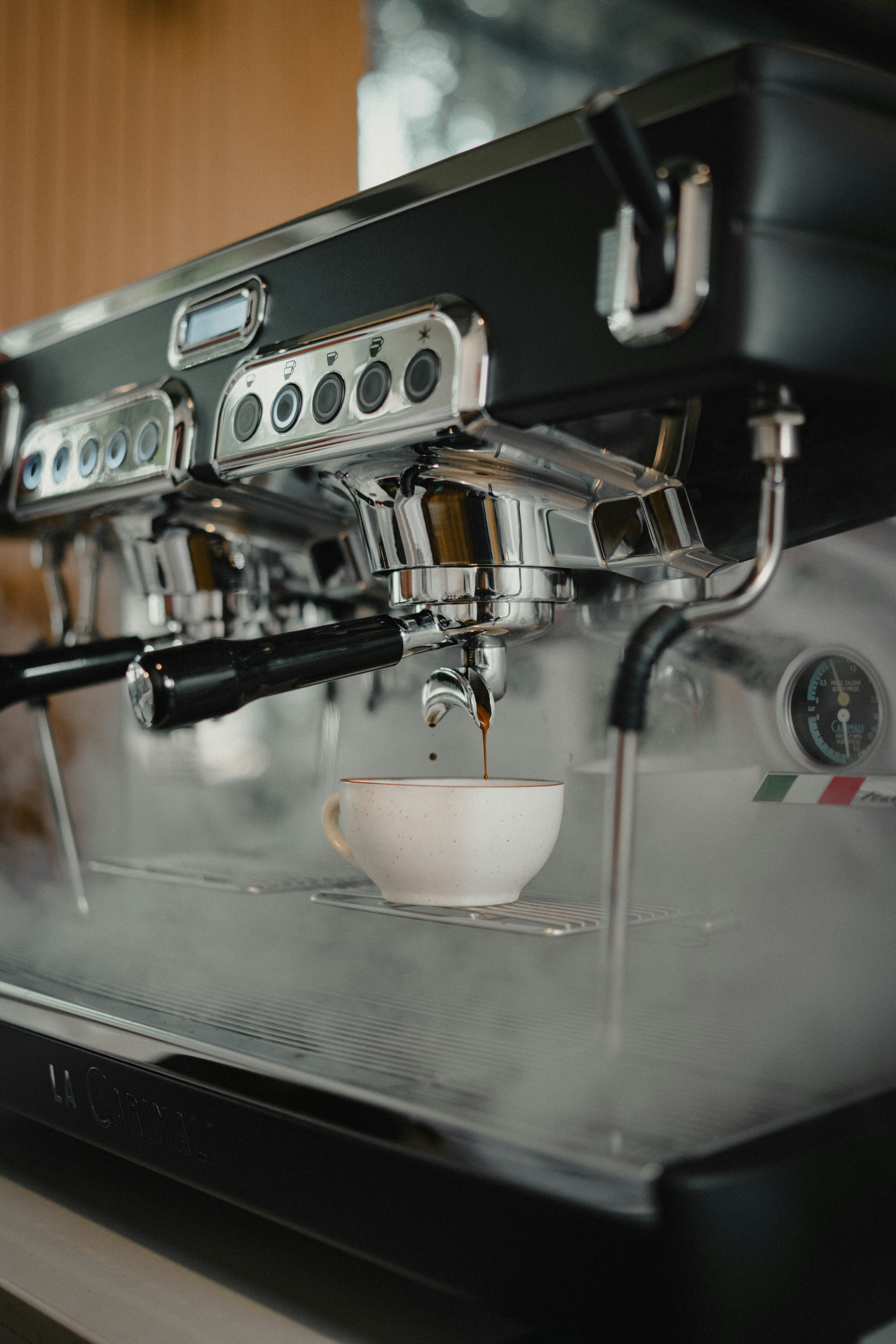 Espresso being brewed into a white cup from machine