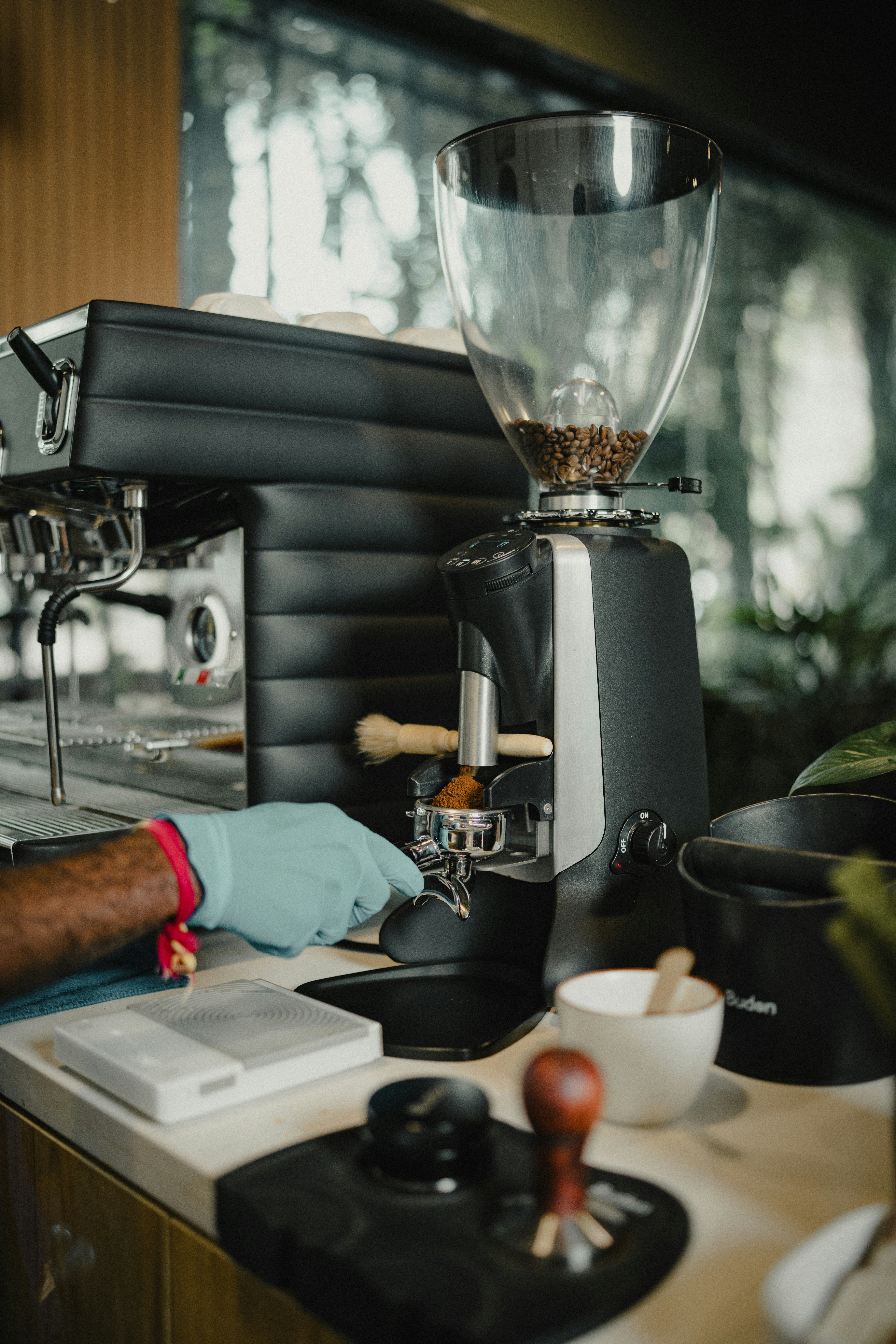 Barista preparing espresso with a coffee grinder and machine.