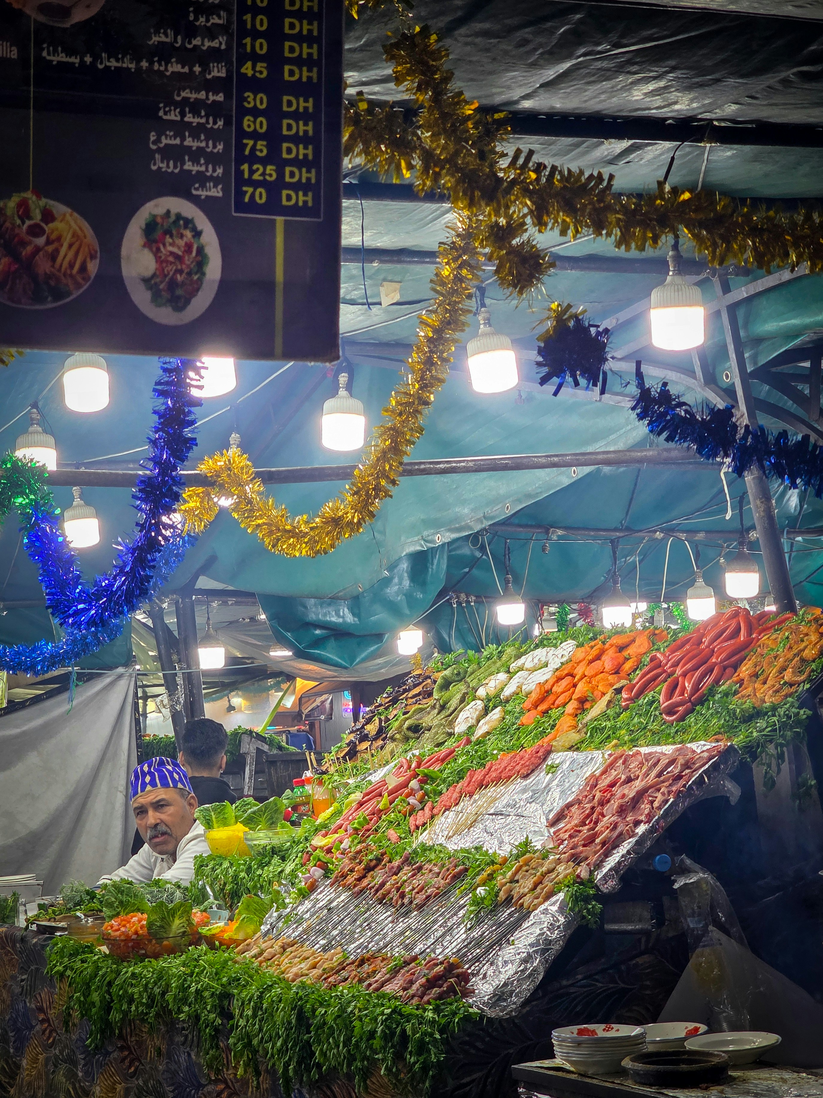 A food stall with colorful raw meats and vegetables.
