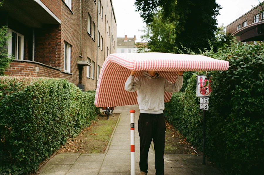 Man carrying a mattress along a sidewalk