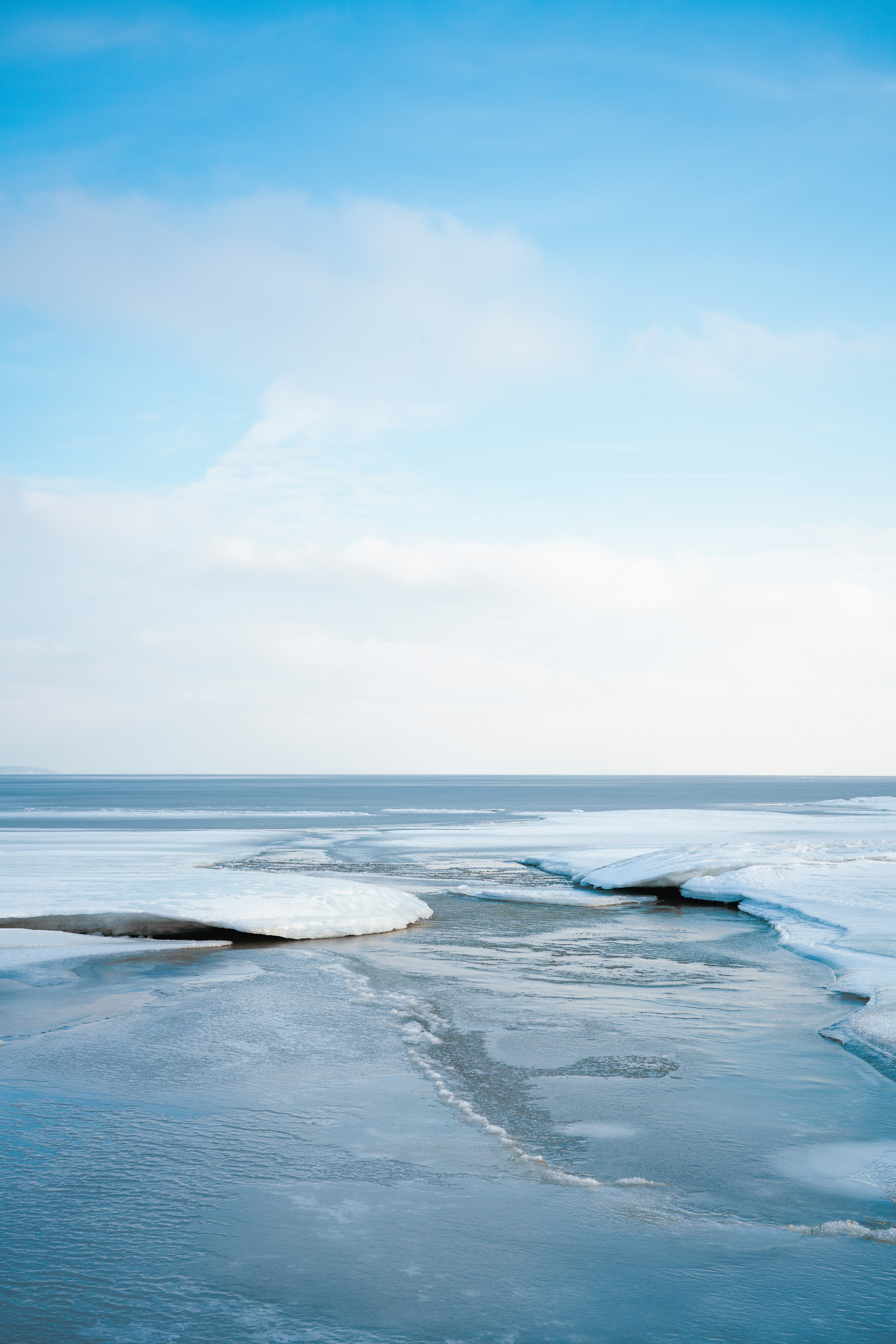 Frozen sea with ice floes under a pale blue sky