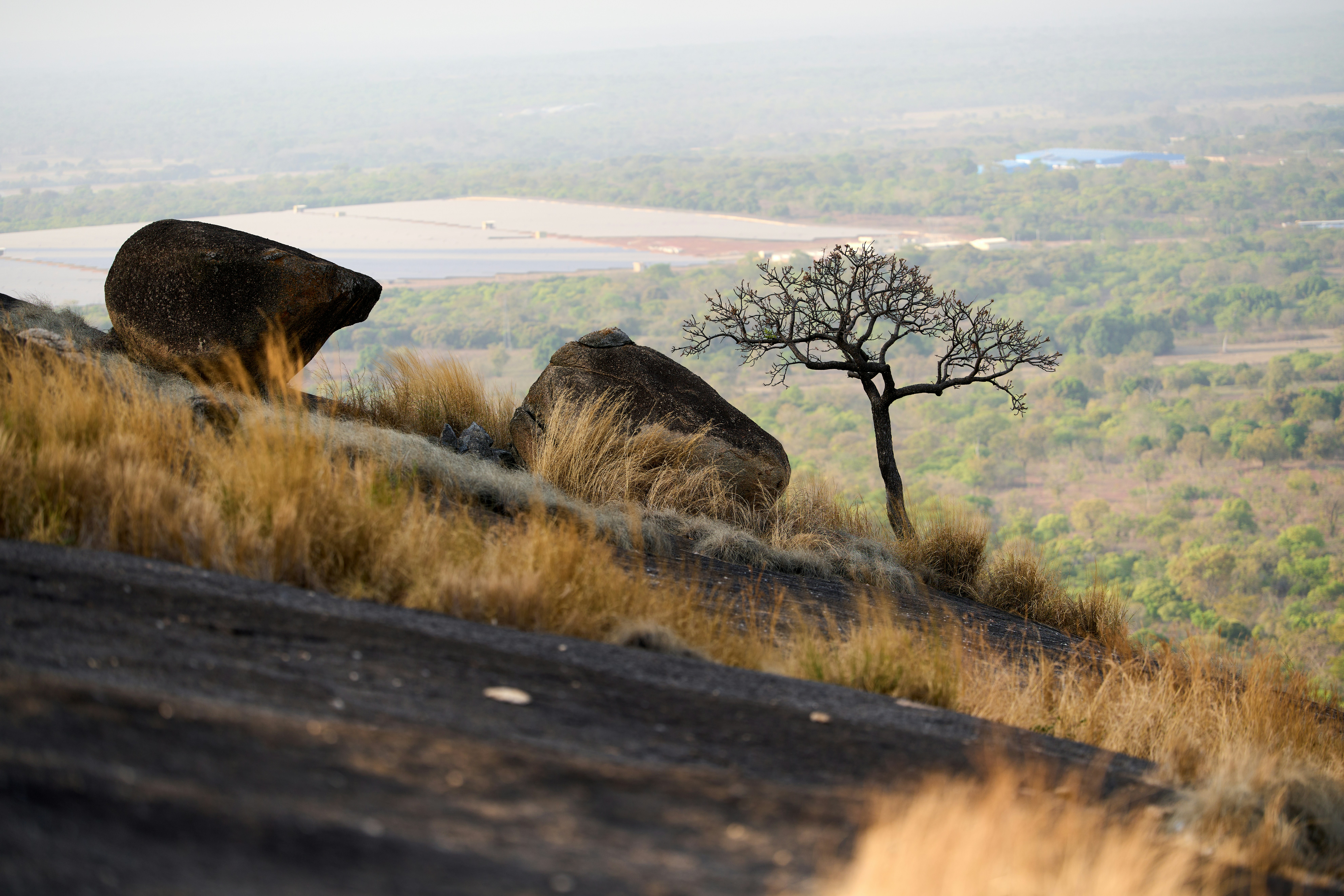 Two large rocks on a grassy hill overlooking a valley.