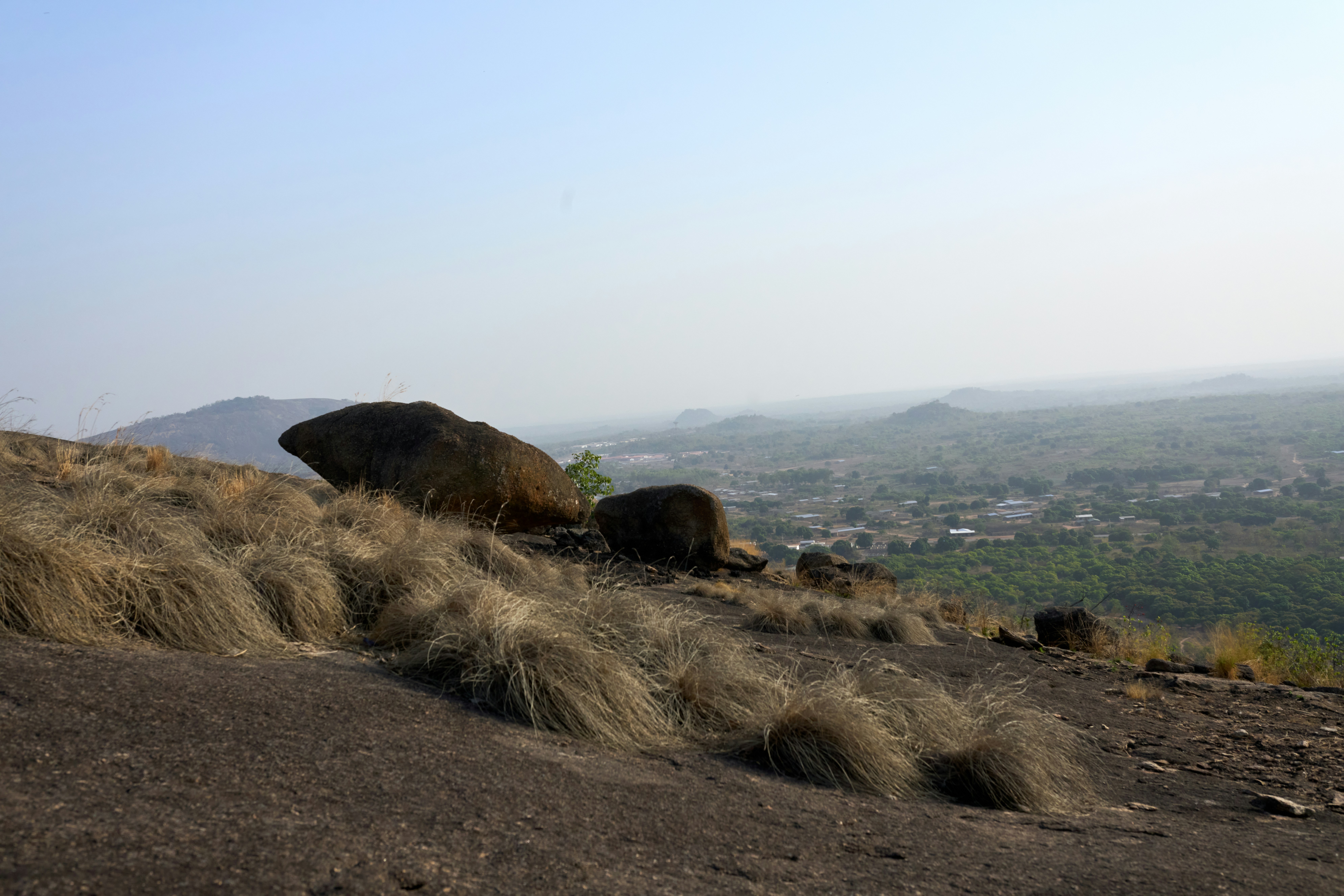 Rocky outcrop with dry grass overlooking distant town