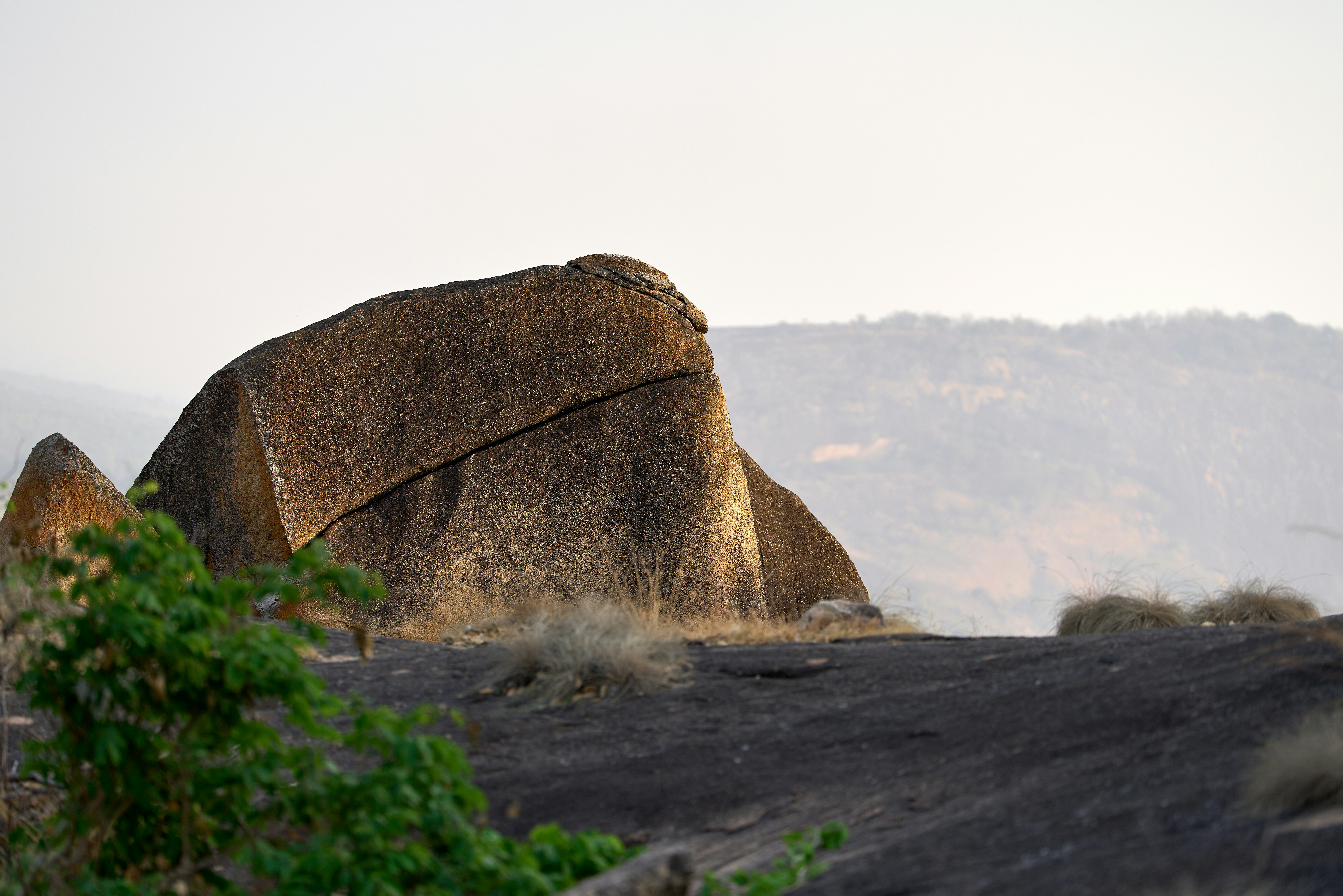Large boulder on a rocky hillside with distant trees
