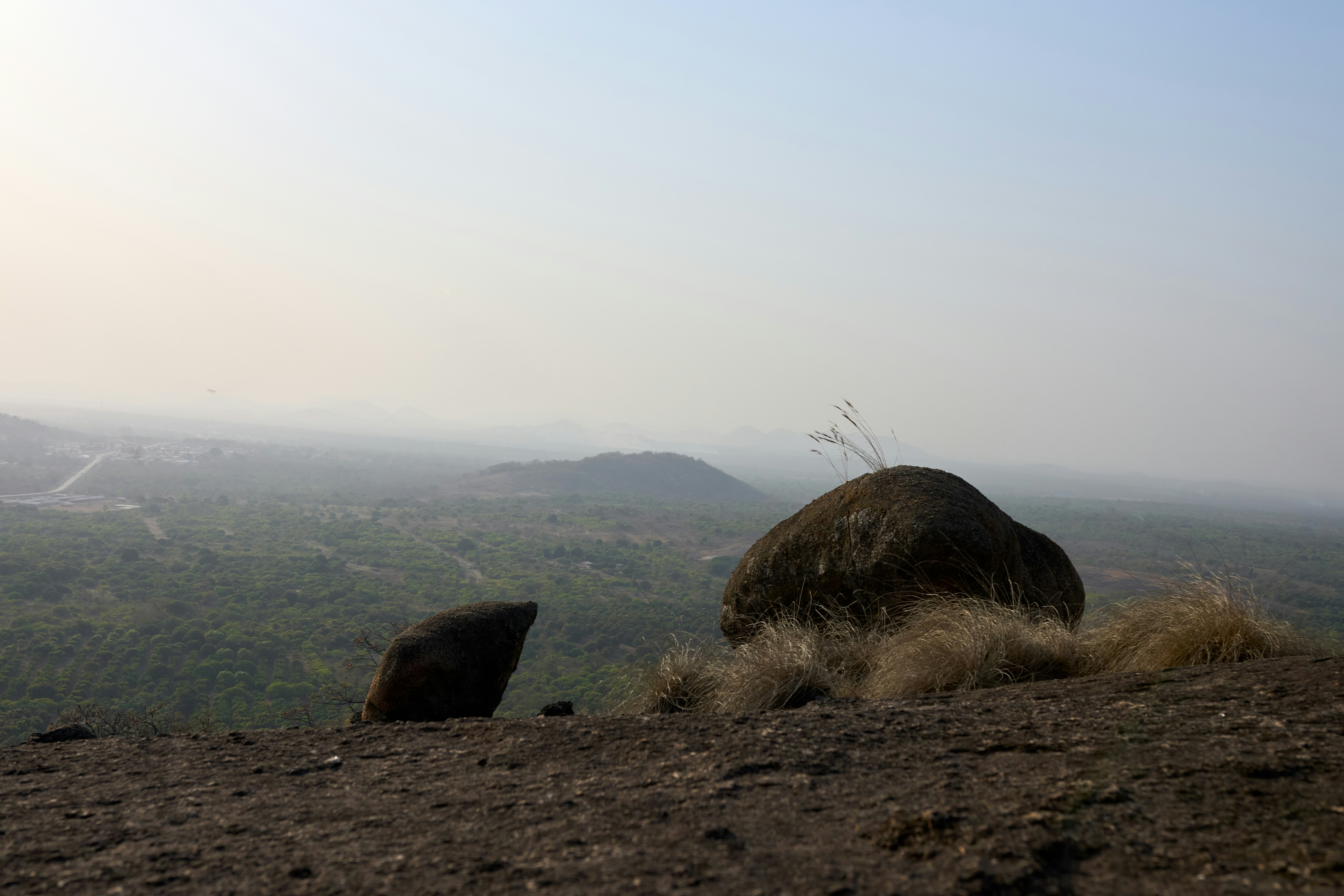 Rocky outcrop overlooking a hazy green landscape