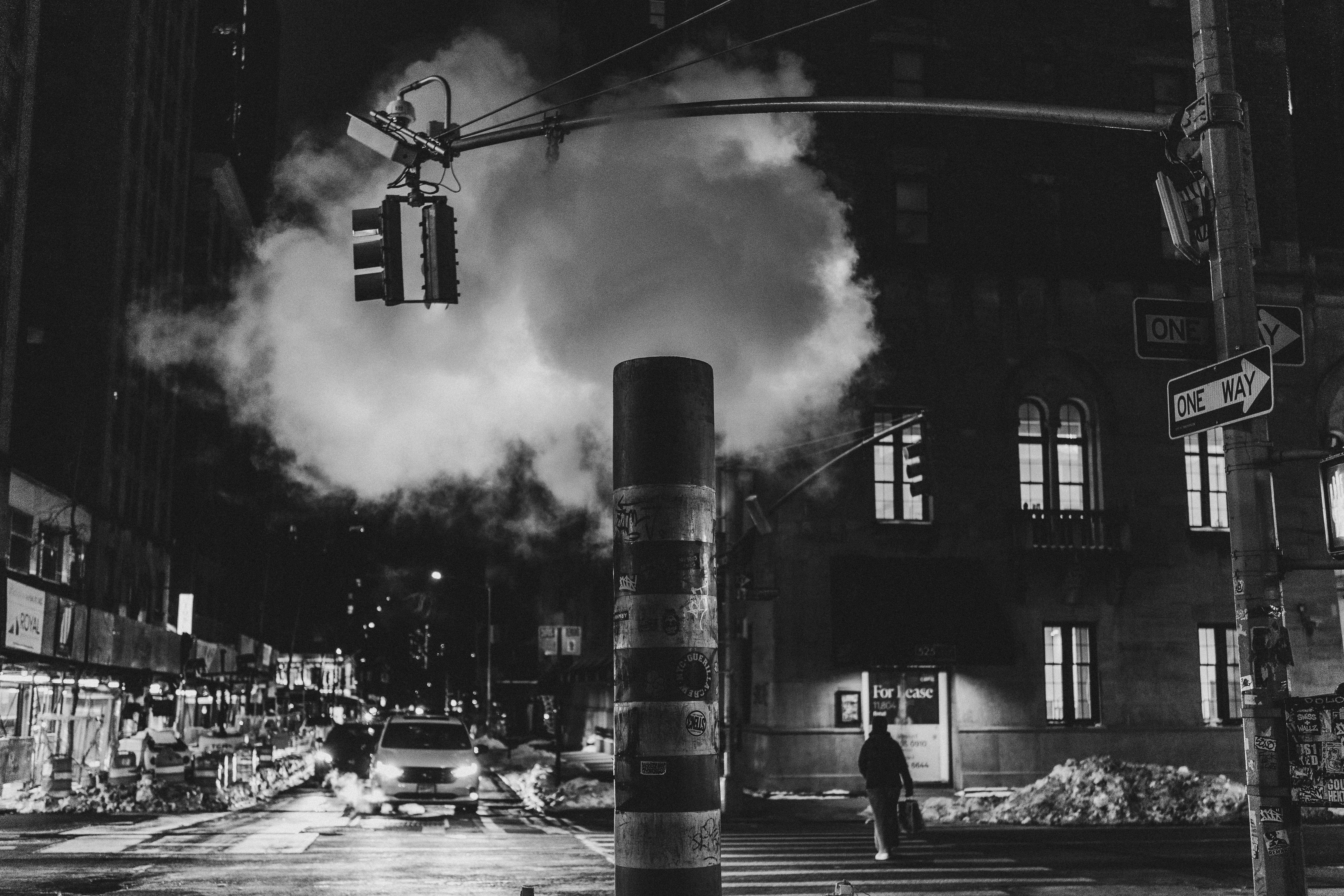De la vapeur s’échappe d’une bouche d’aération de rue la nuit.