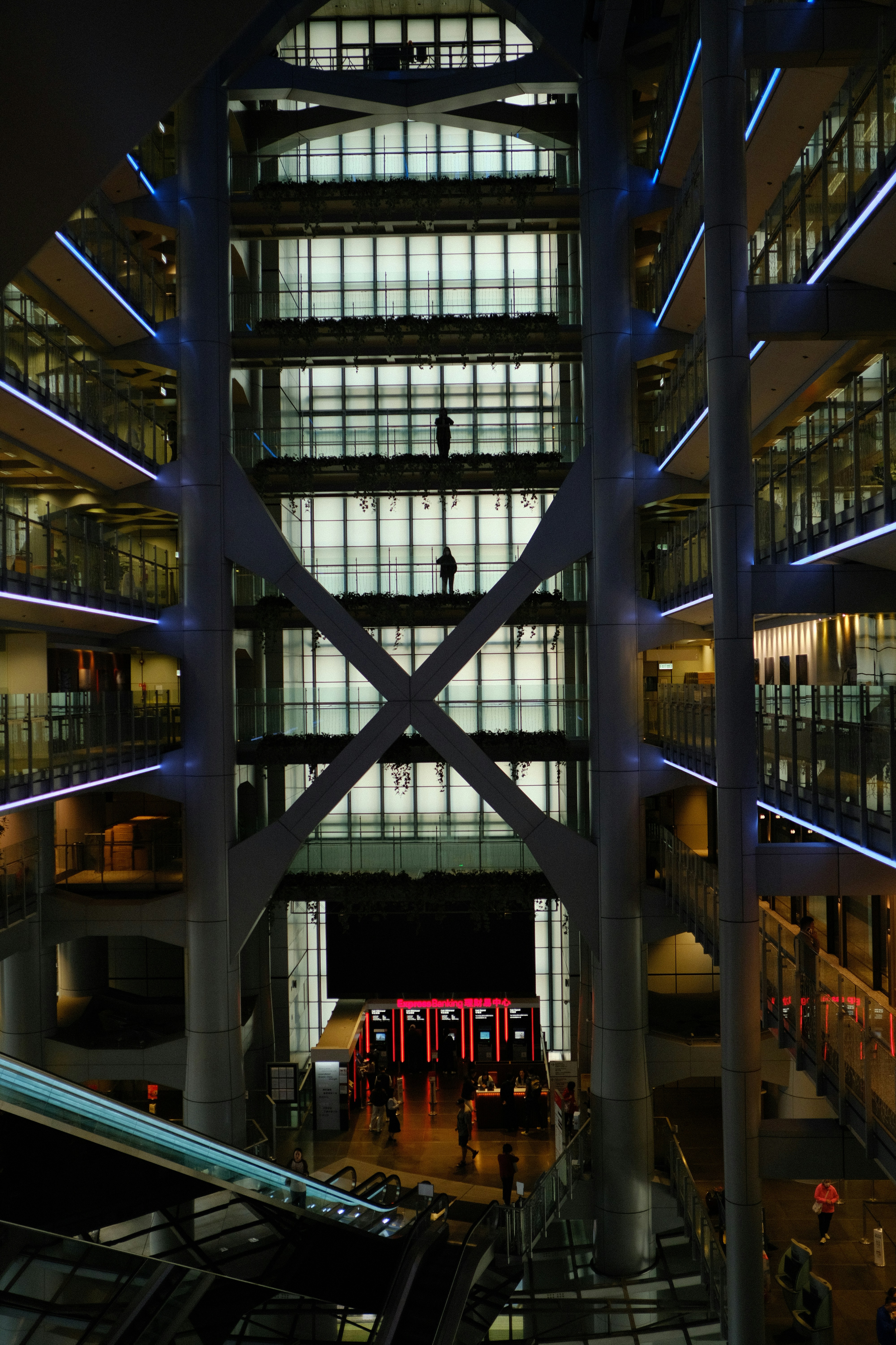 Modern building interior with escalators and illuminated floors.