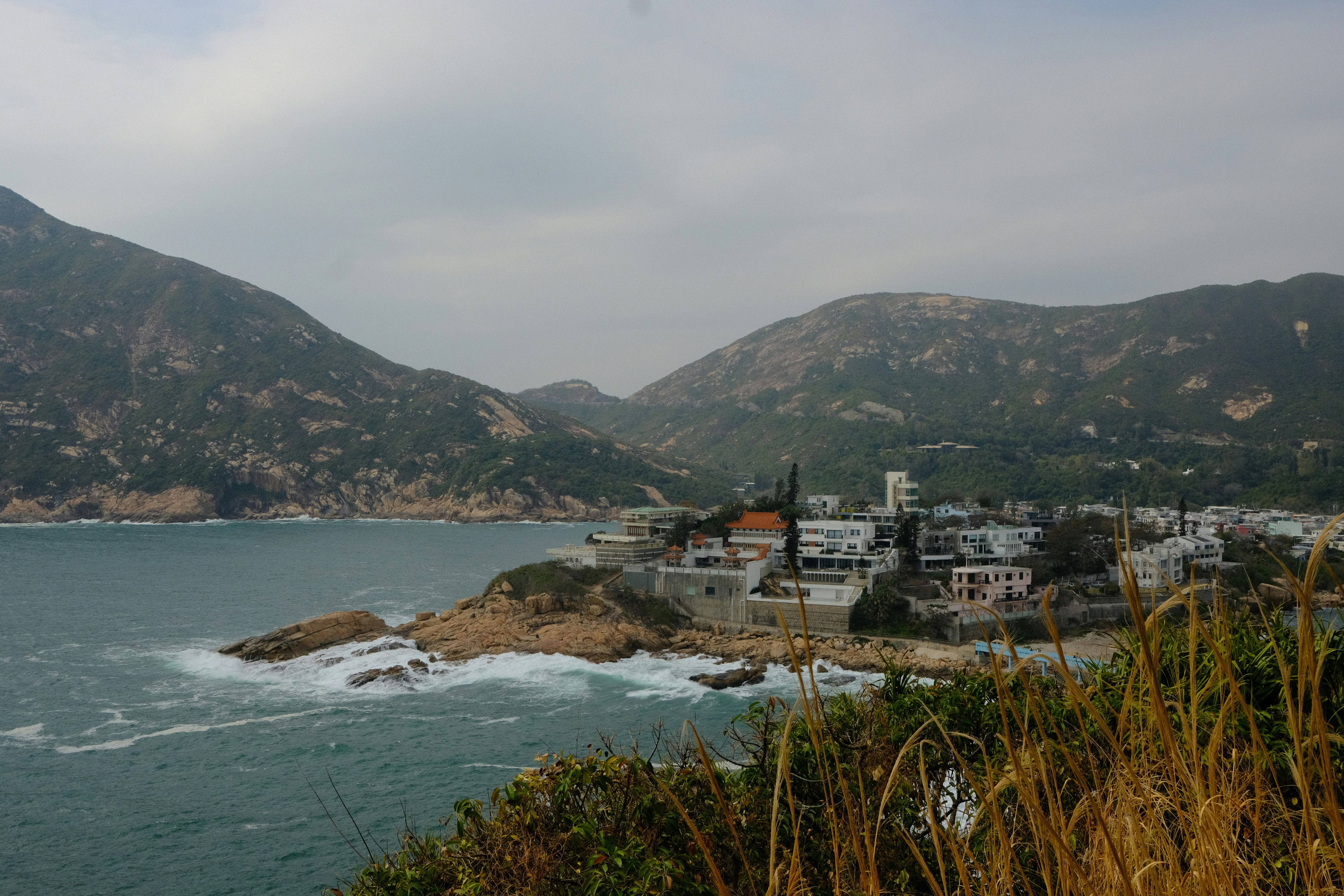 Coastal village nestled among rocky hills under cloudy sky