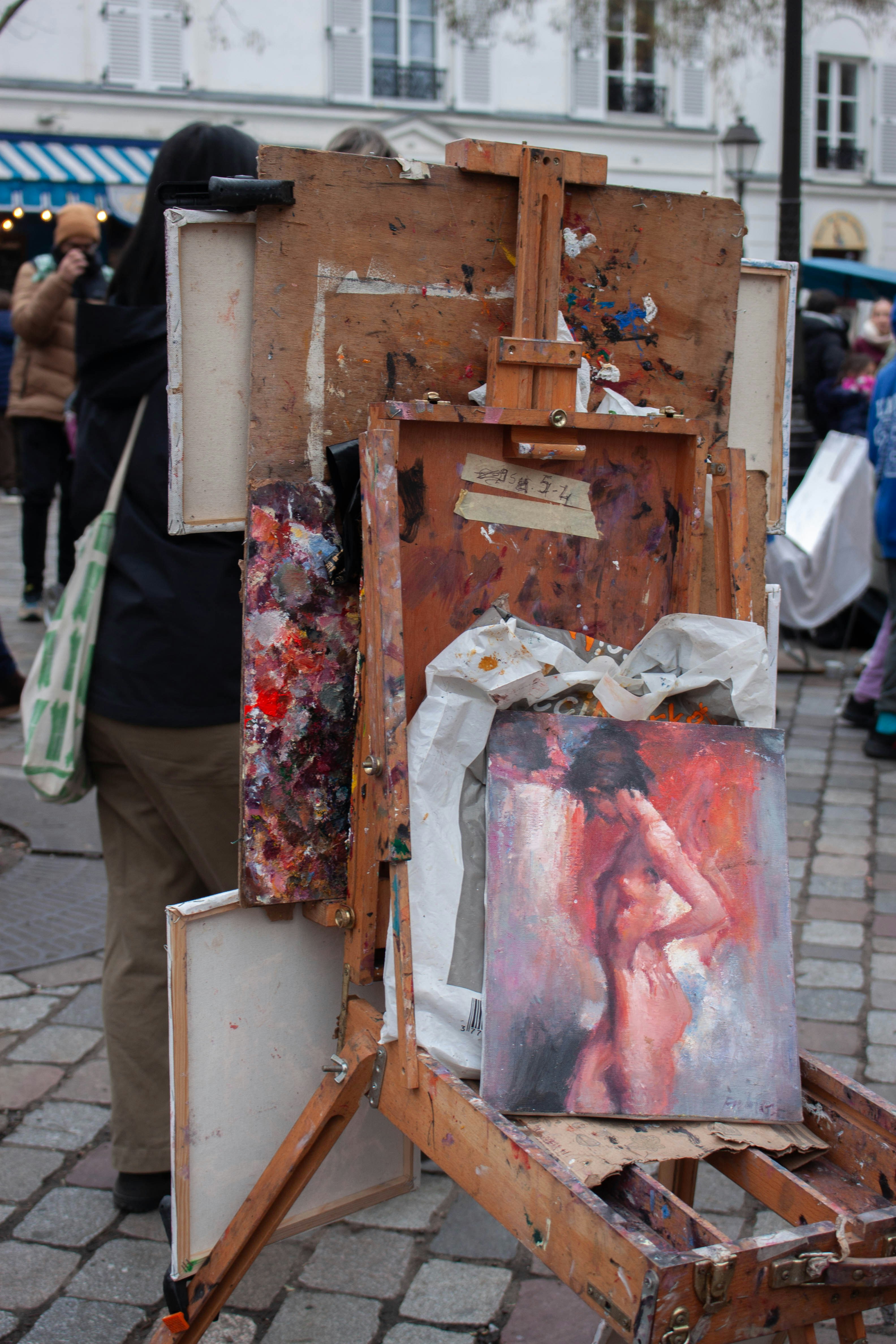 Artist painting a nude figure on an easel outdoors