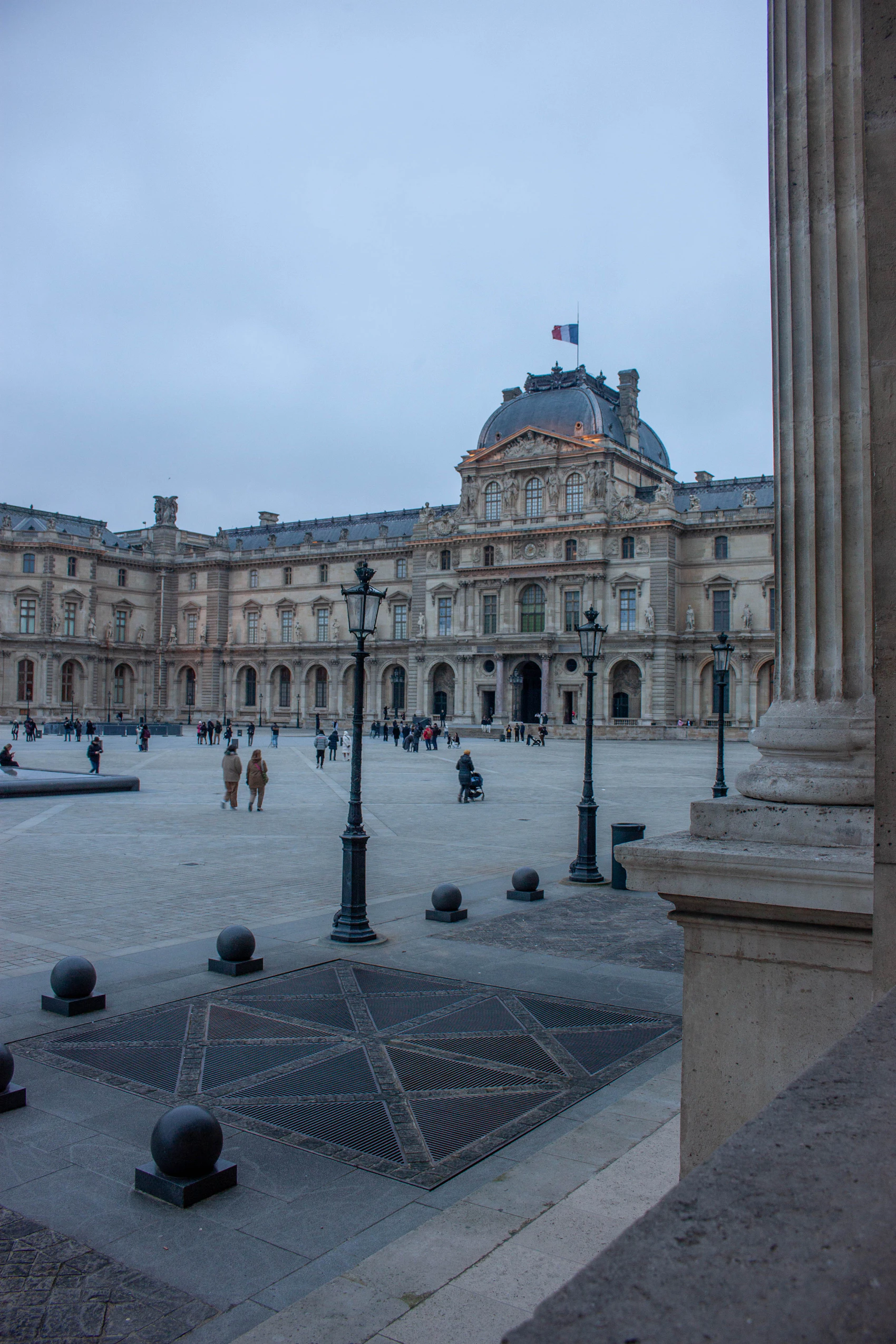 Visitors crossing the Louvre courtyard between the historic façades and glass pyramid