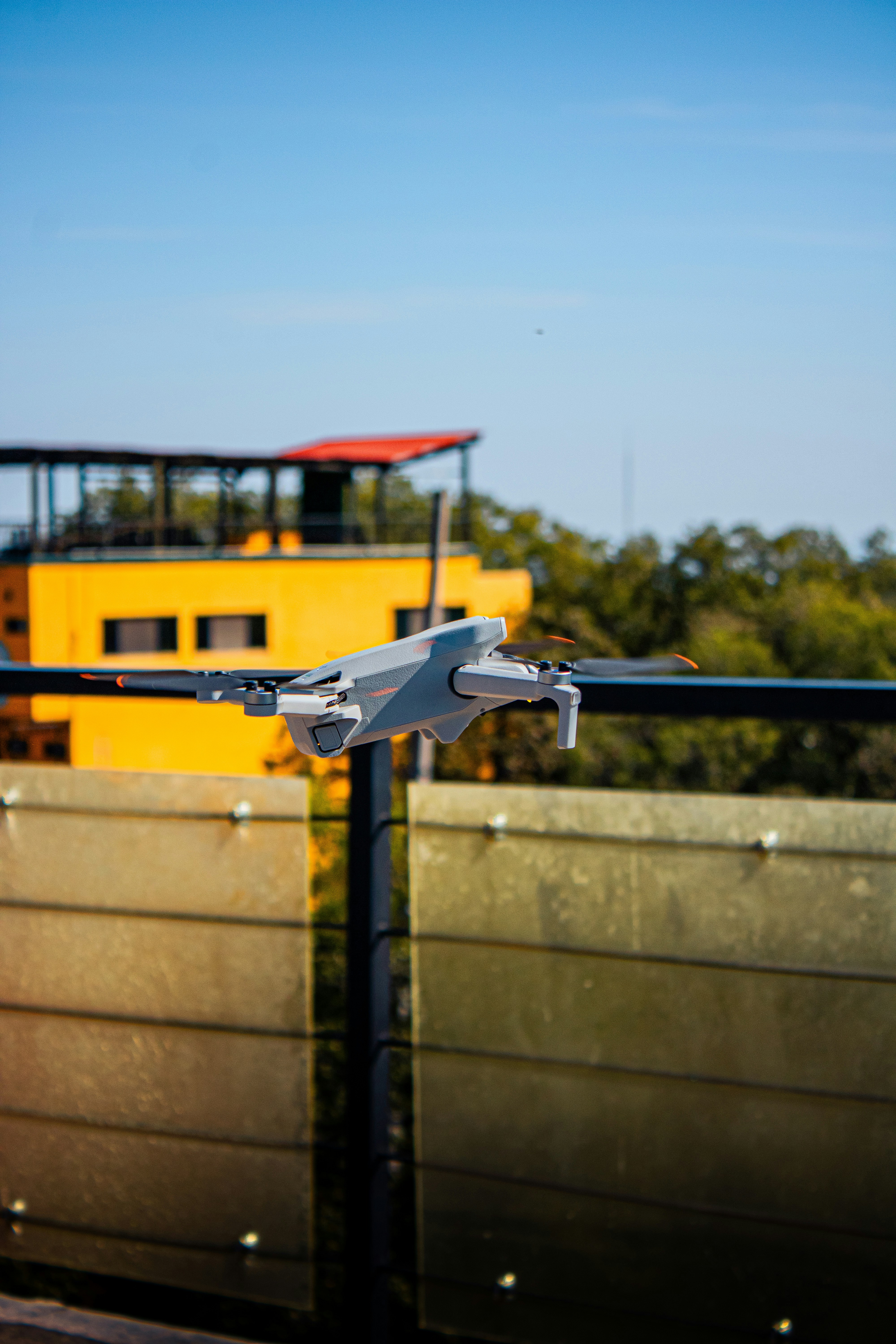 A white drone rests on a railing outdoors.
