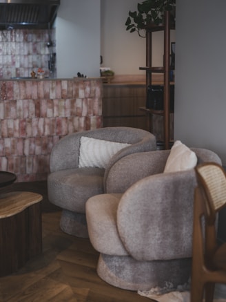 Two plush armchairs with pillows in a cozy room.