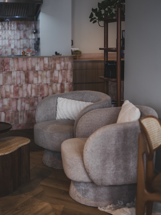 Two plush armchairs with pillows in a cozy room.