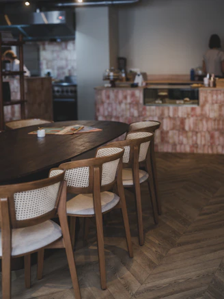Wooden chairs around a dark oval table in cafe.