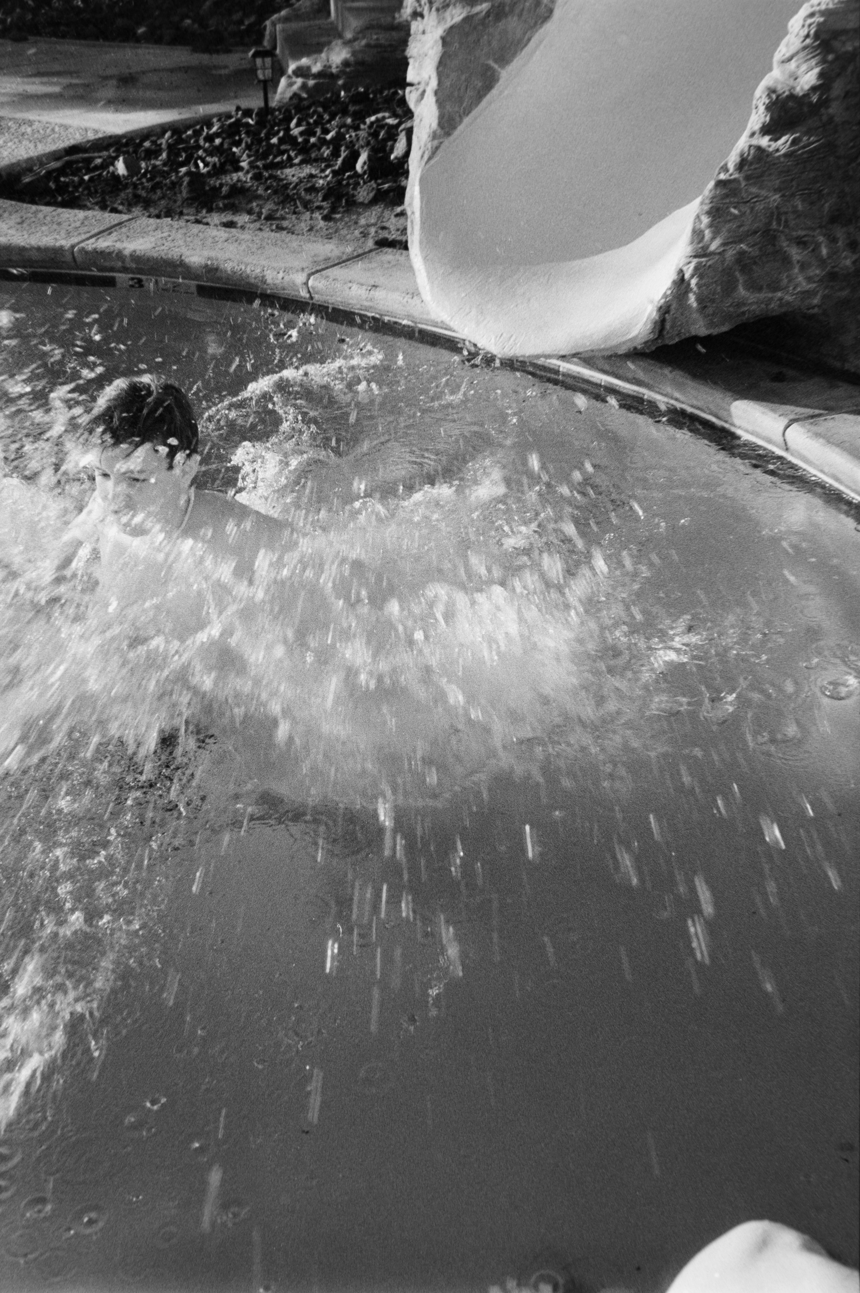 Child splashing into a swimming pool from a slide.