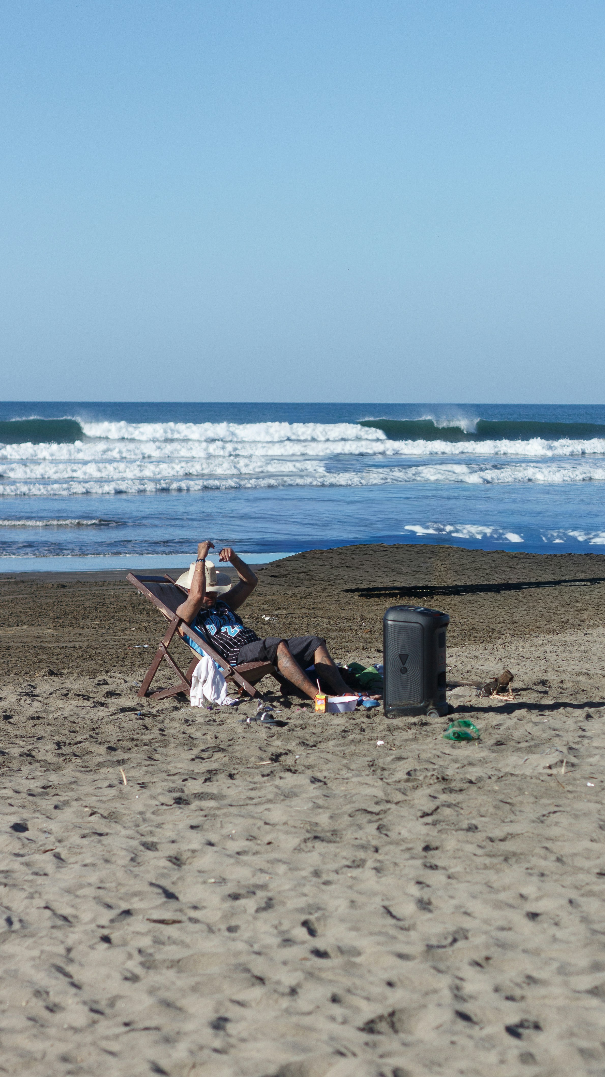 Man relaxing on beach chair by the ocean waves.