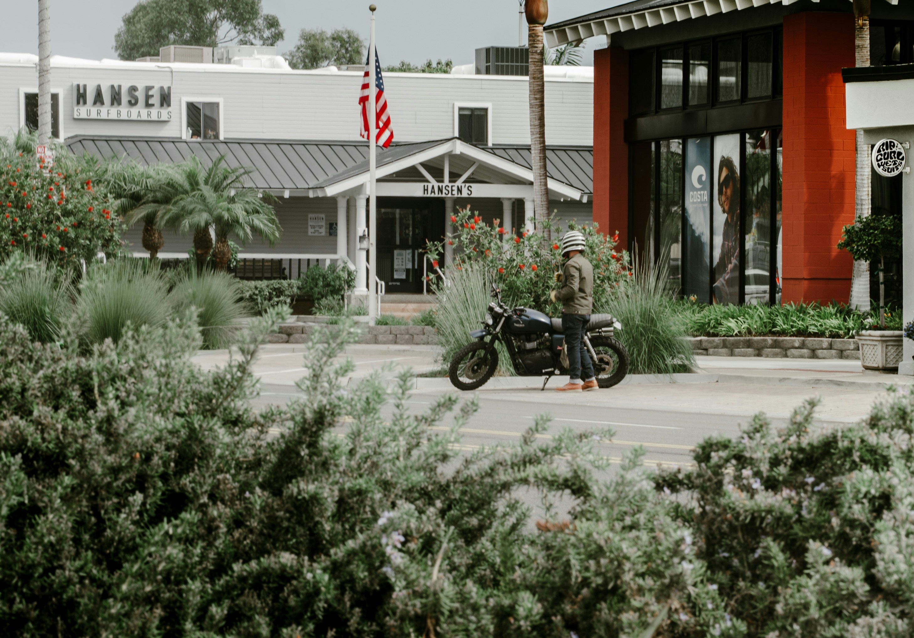 Man standing next to motorcycle outside hansen building.