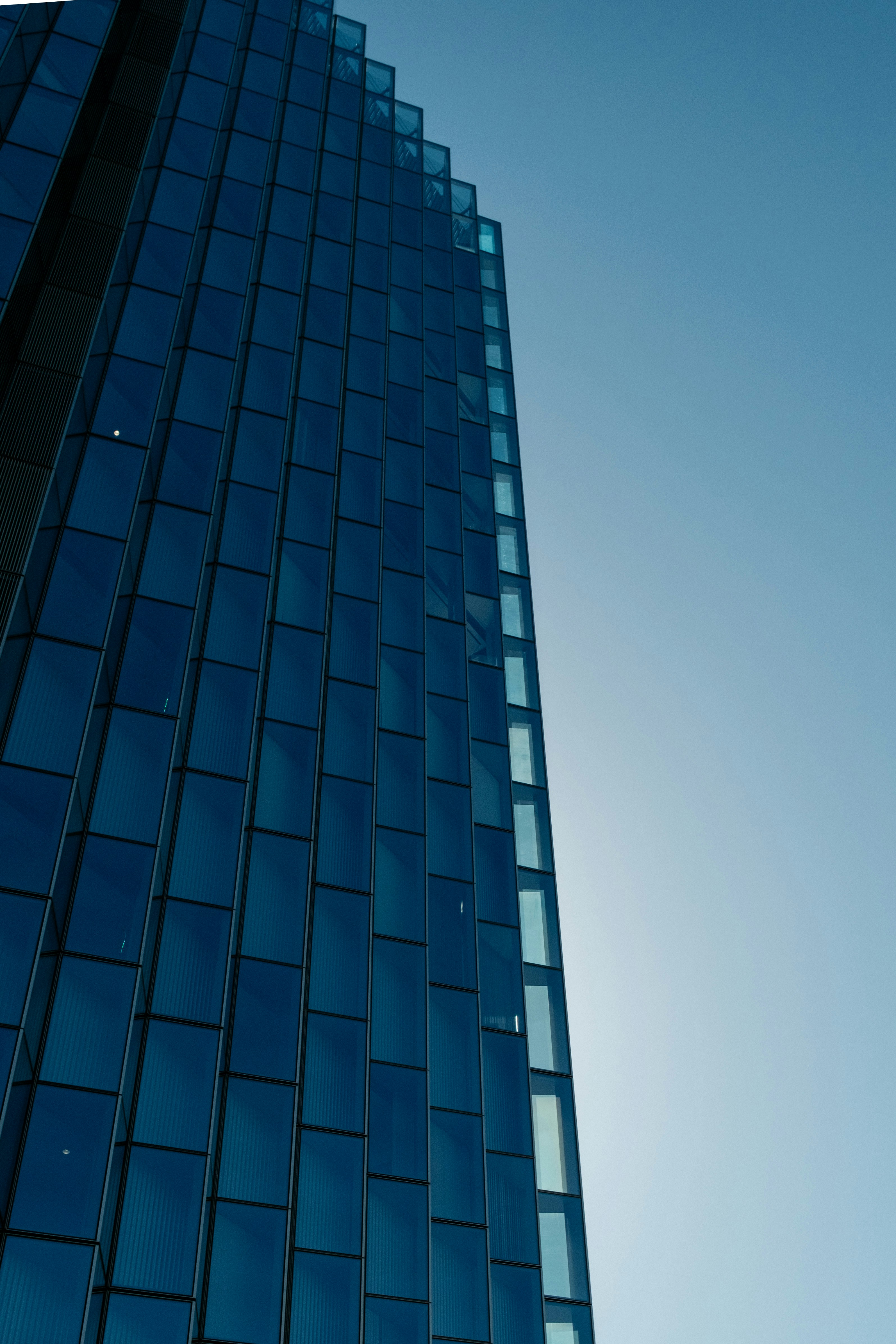 Modern glass skyscraper against a clear blue sky.