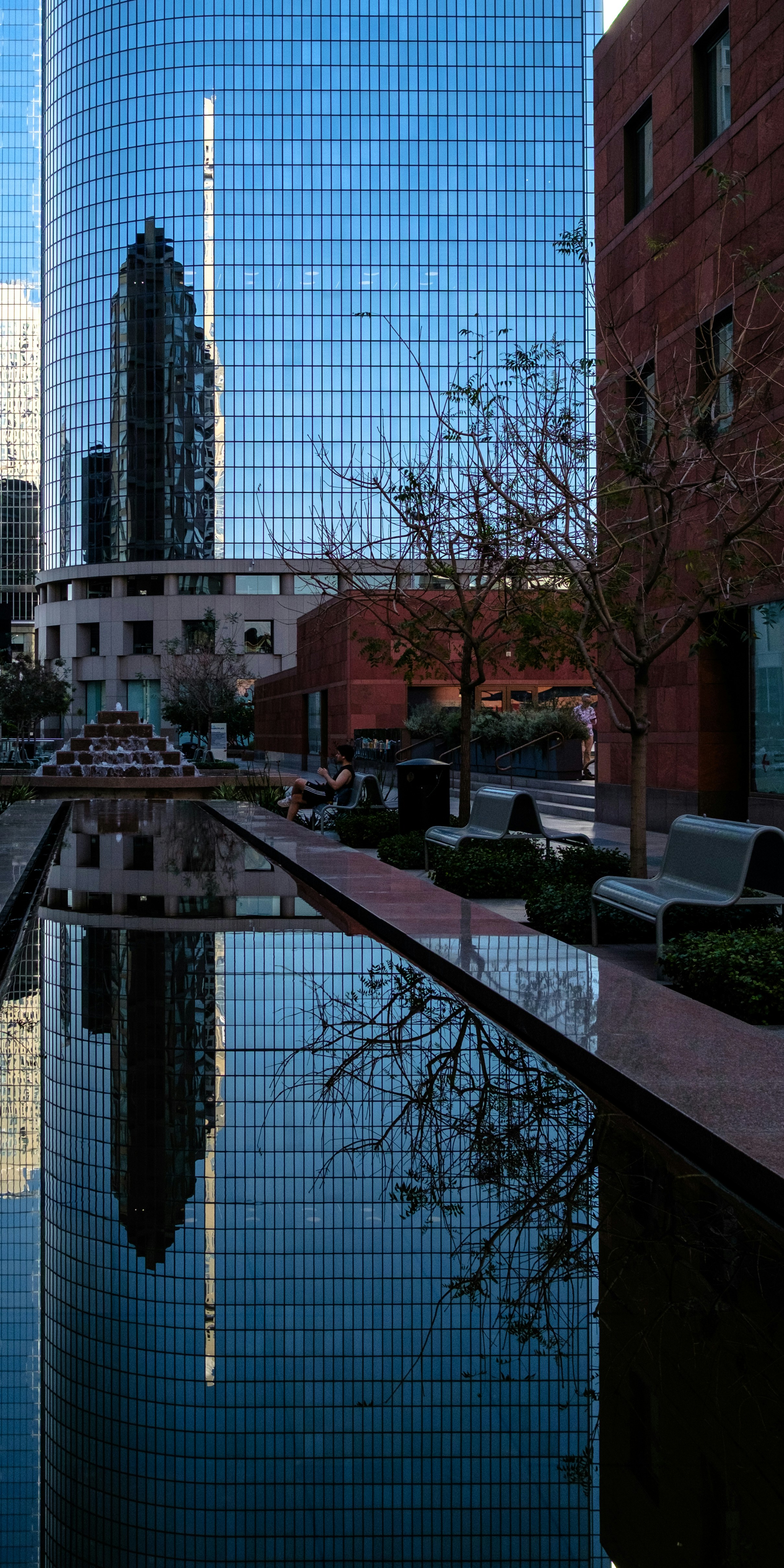 Glass skyscraper reflecting in a water feature.