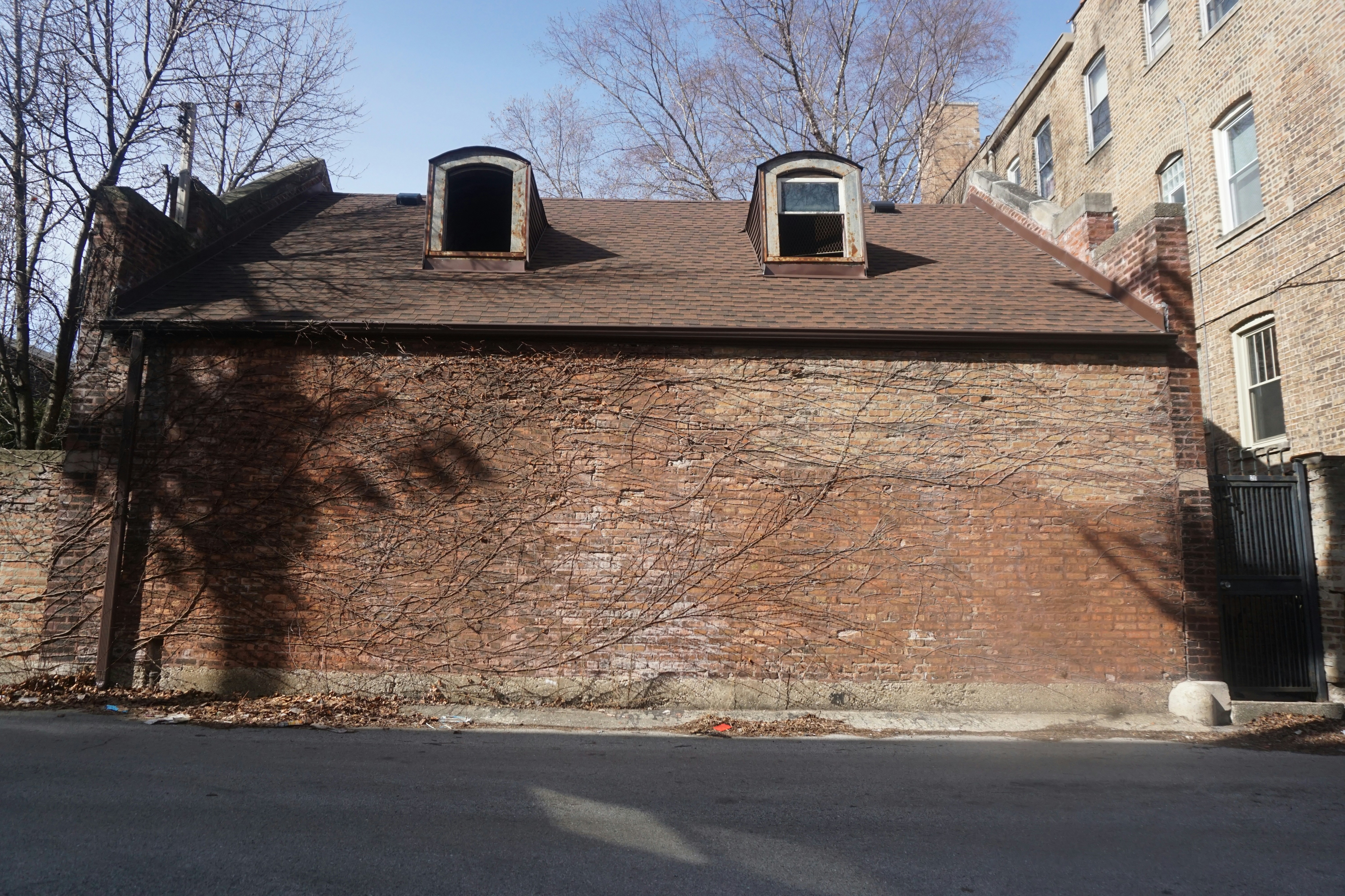 A brick building with dormer windows under a cloudy sky