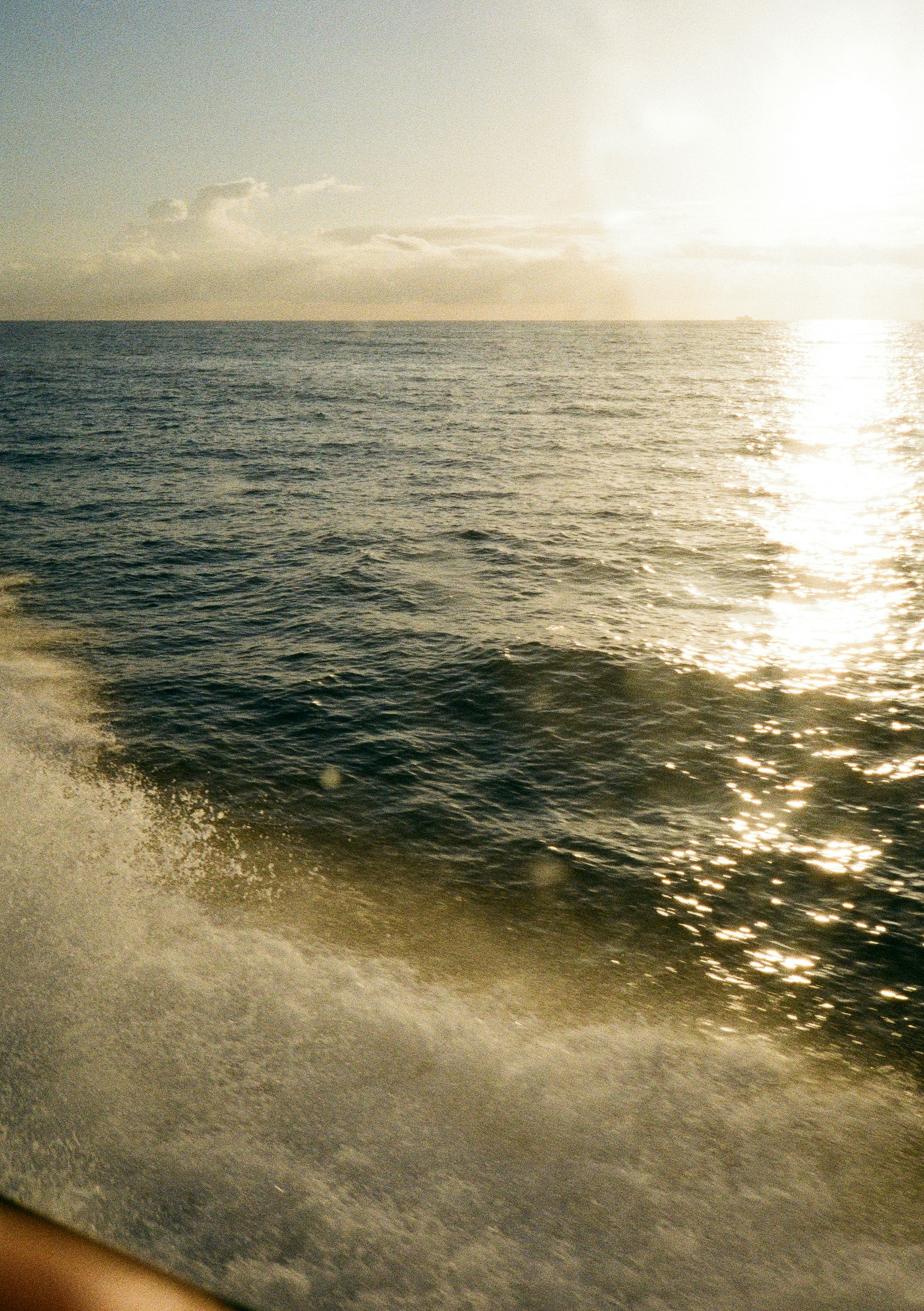 Sunlight glinting on ocean waves from a moving boat