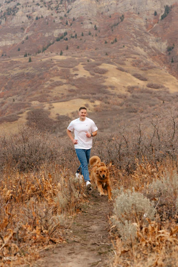 Man and dog running on a mountain trail