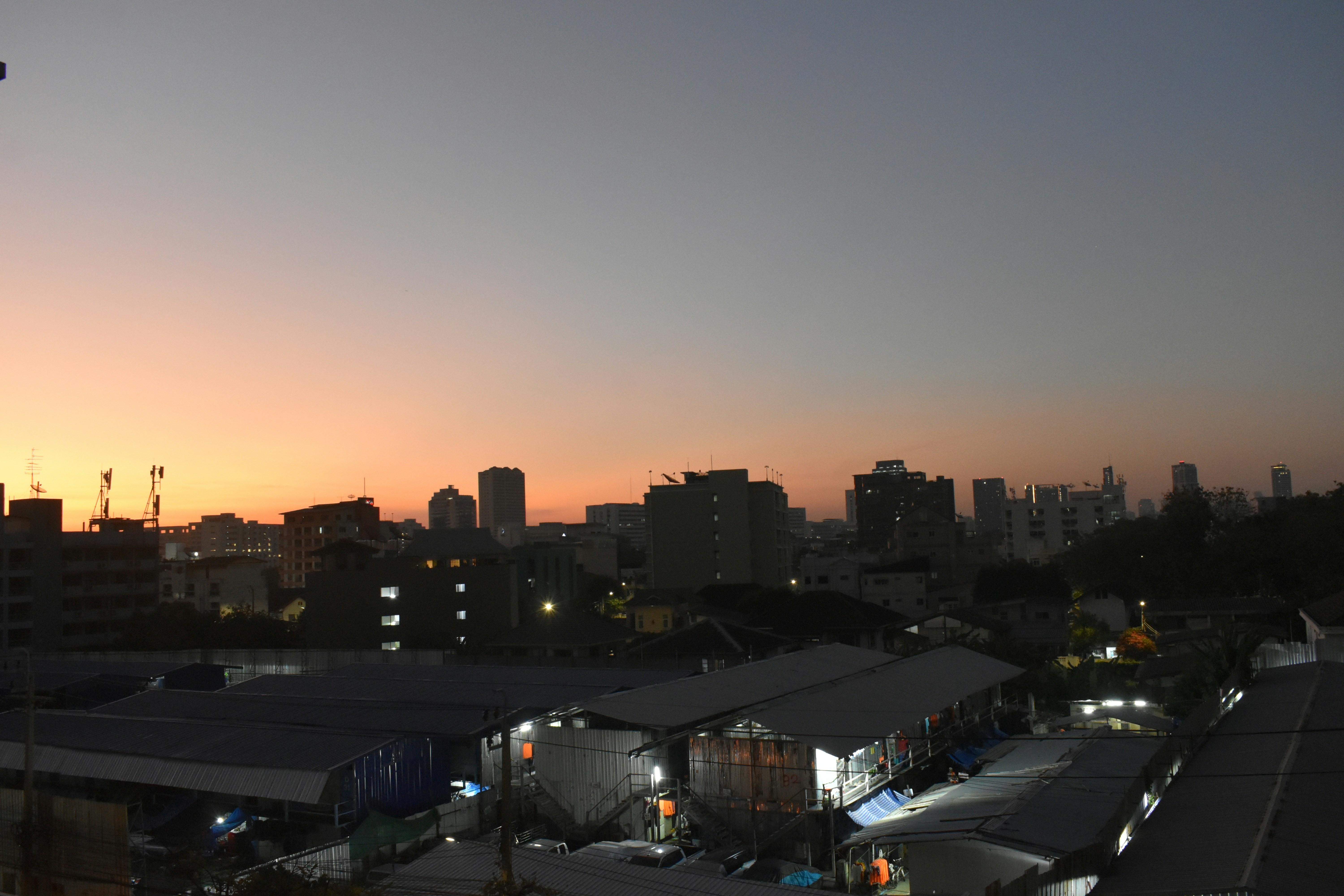 City skyline at dusk with buildings and industrial areas.