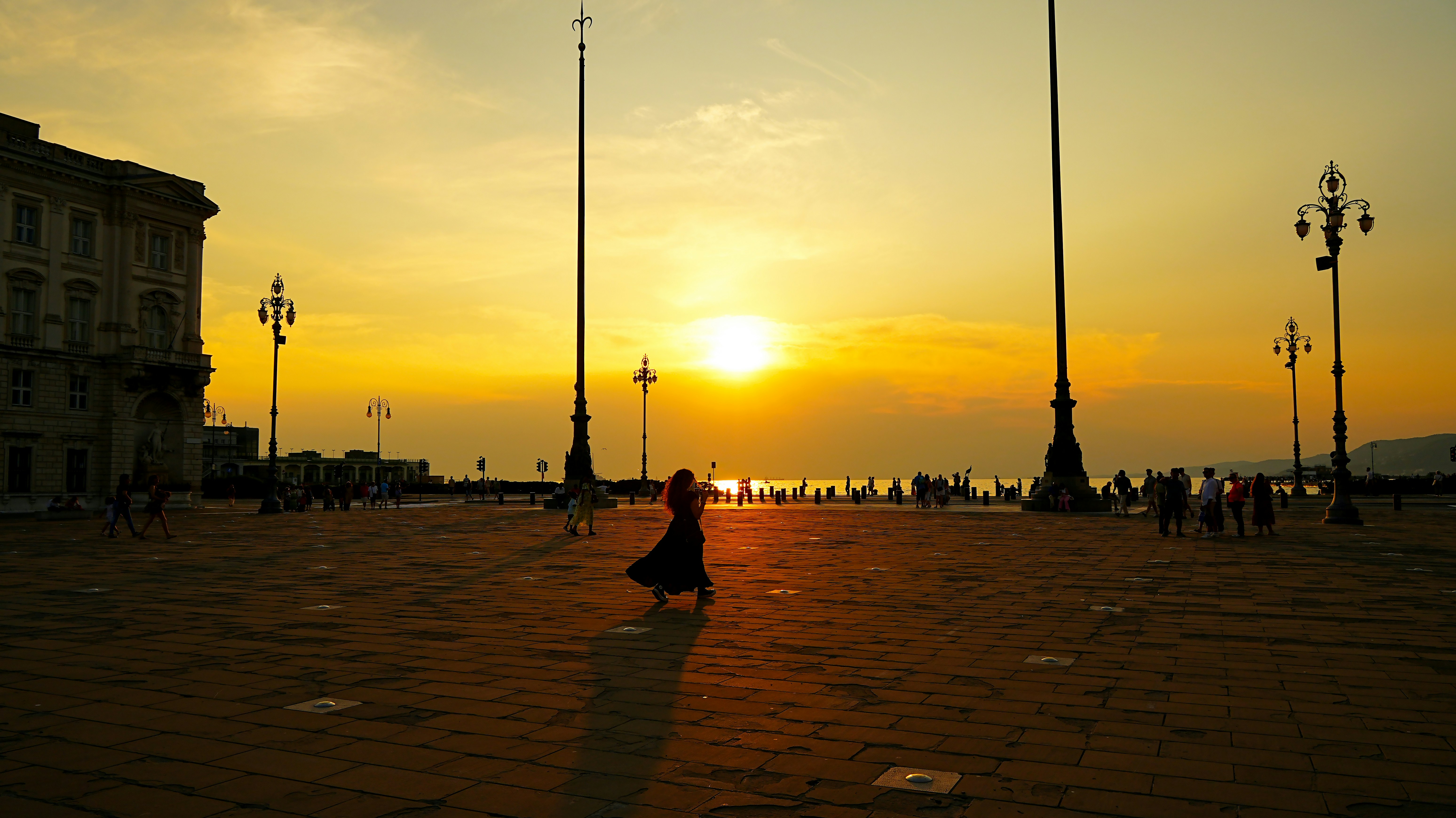 Woman walking in a plaza at sunset