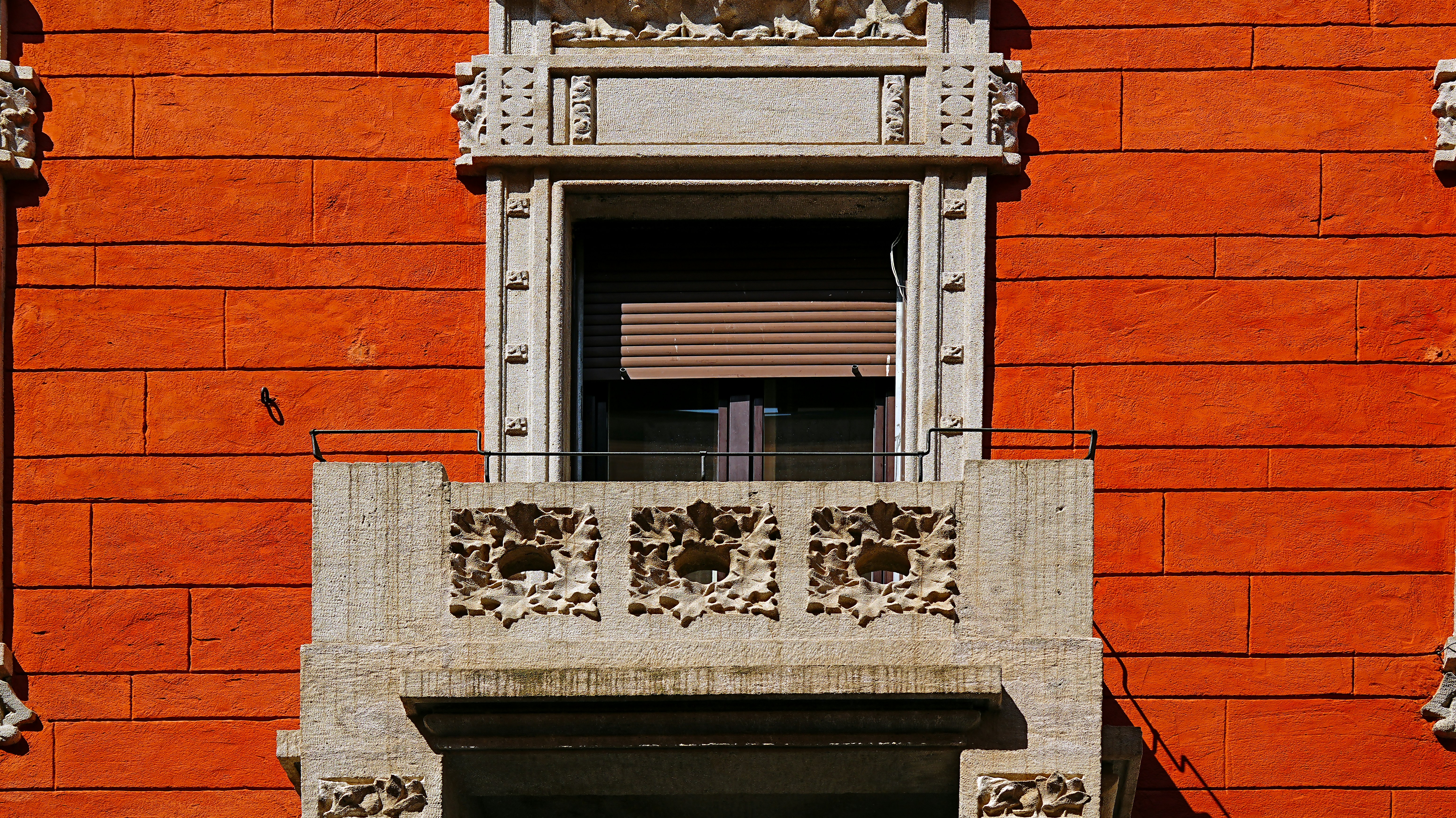 Orange brick building facade with ornate balcony detail