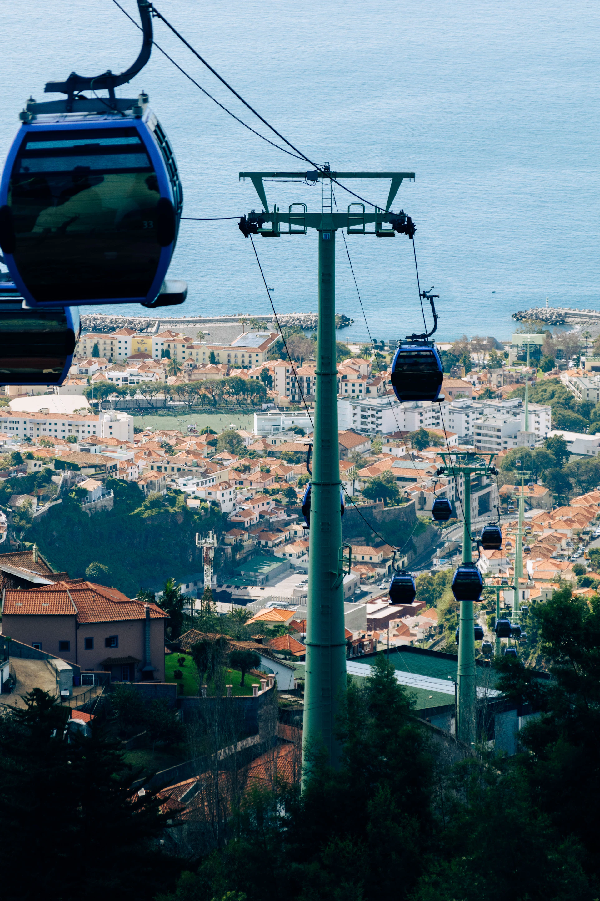 Cable cars ascend over a coastal city with ocean background.