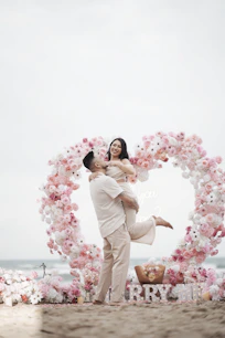Couple embracing on beach with floral heart arch