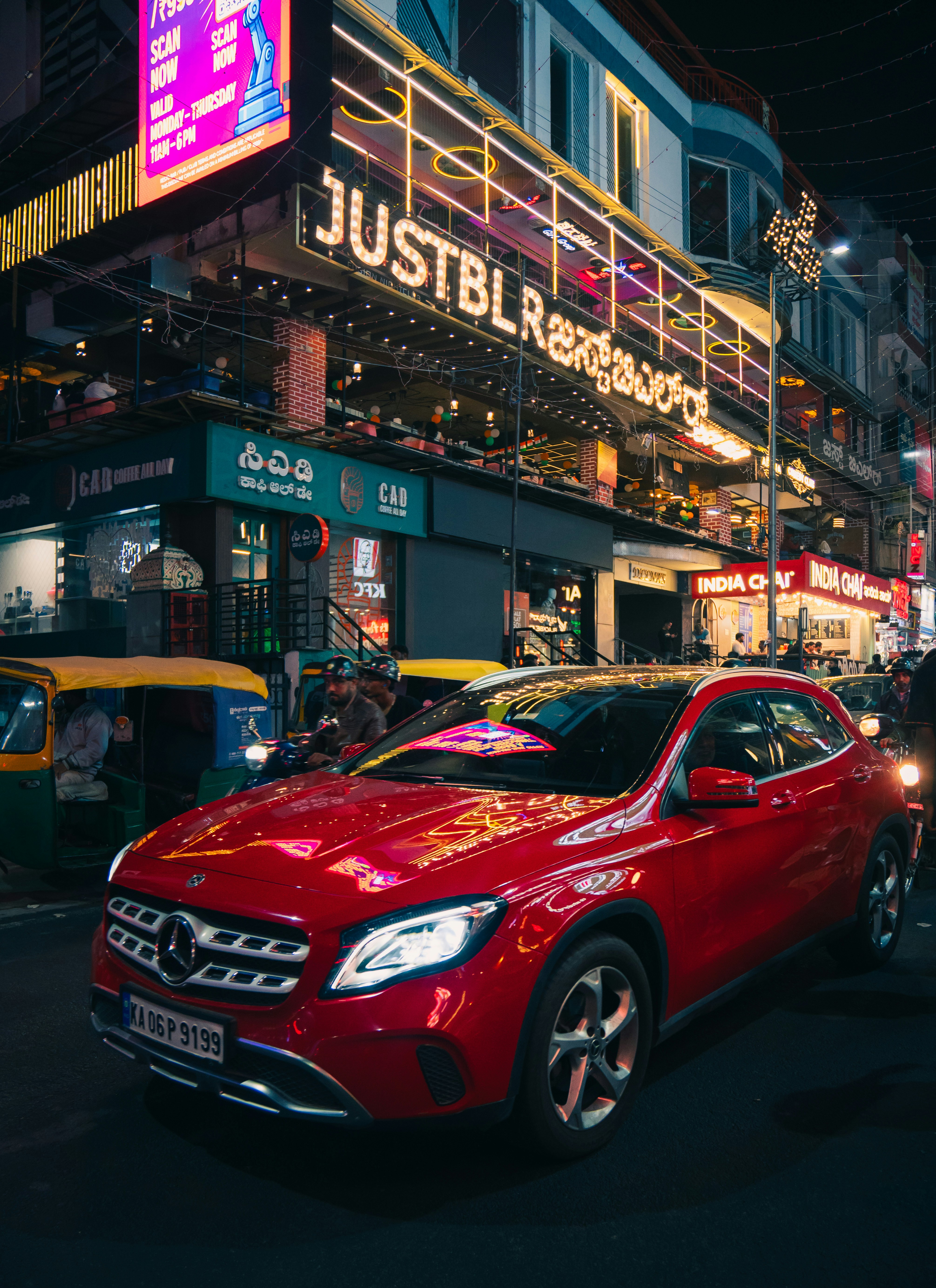 Rotes Auto, das nachts auf einer belebten Stadtstraße geparkt ist