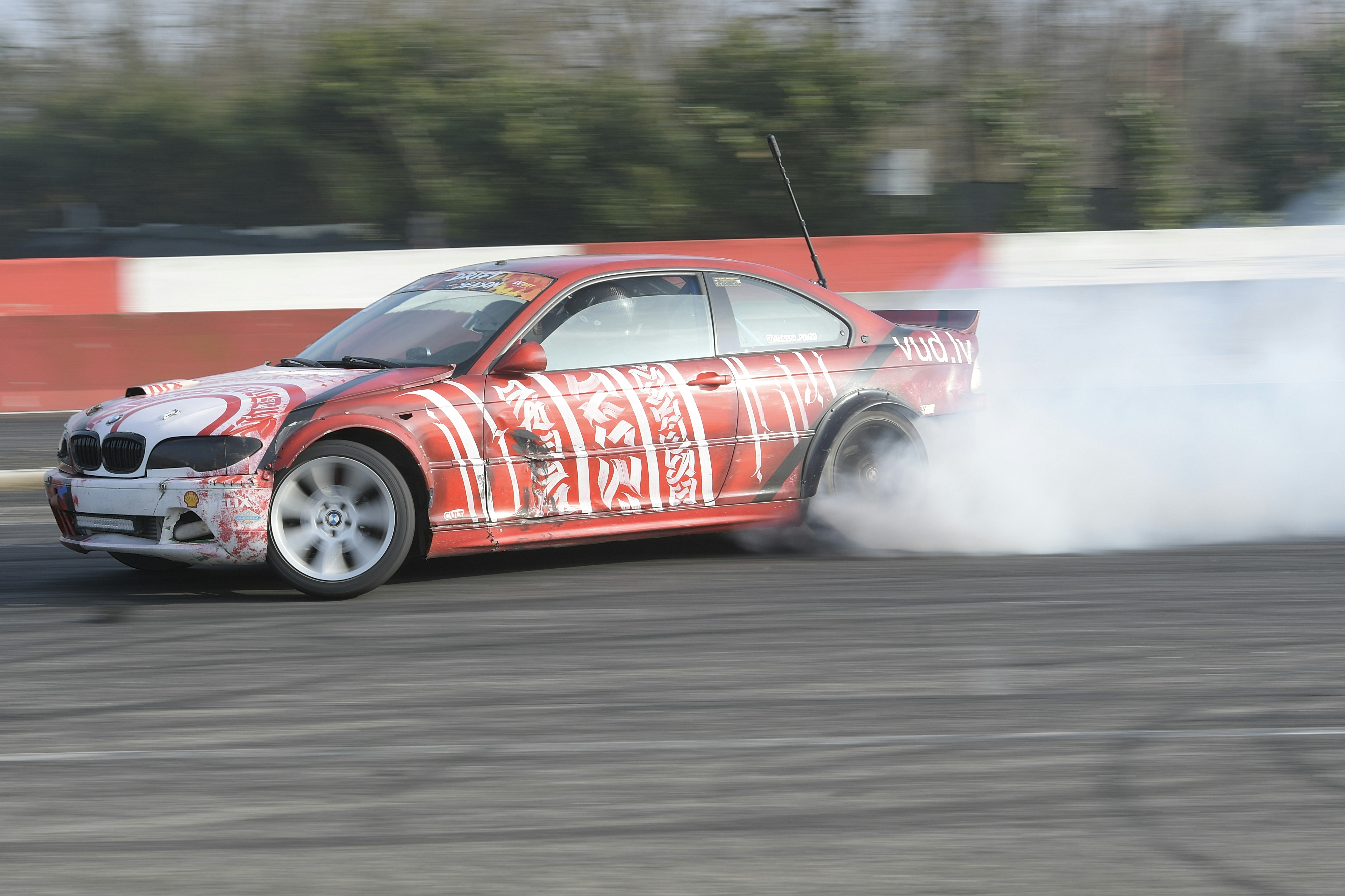 A red race car drifts, creating smoke.