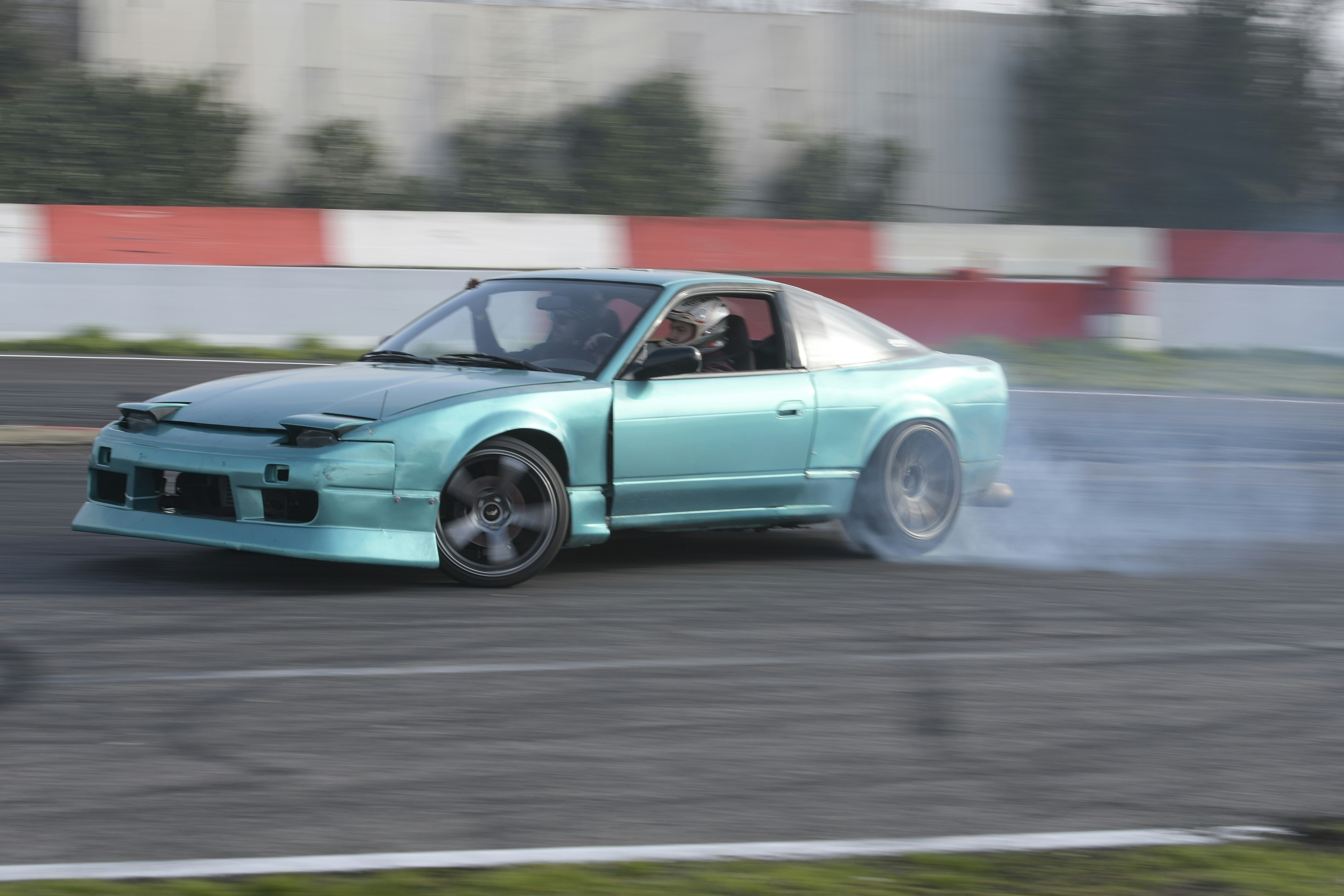 A teal car drifts on a race track