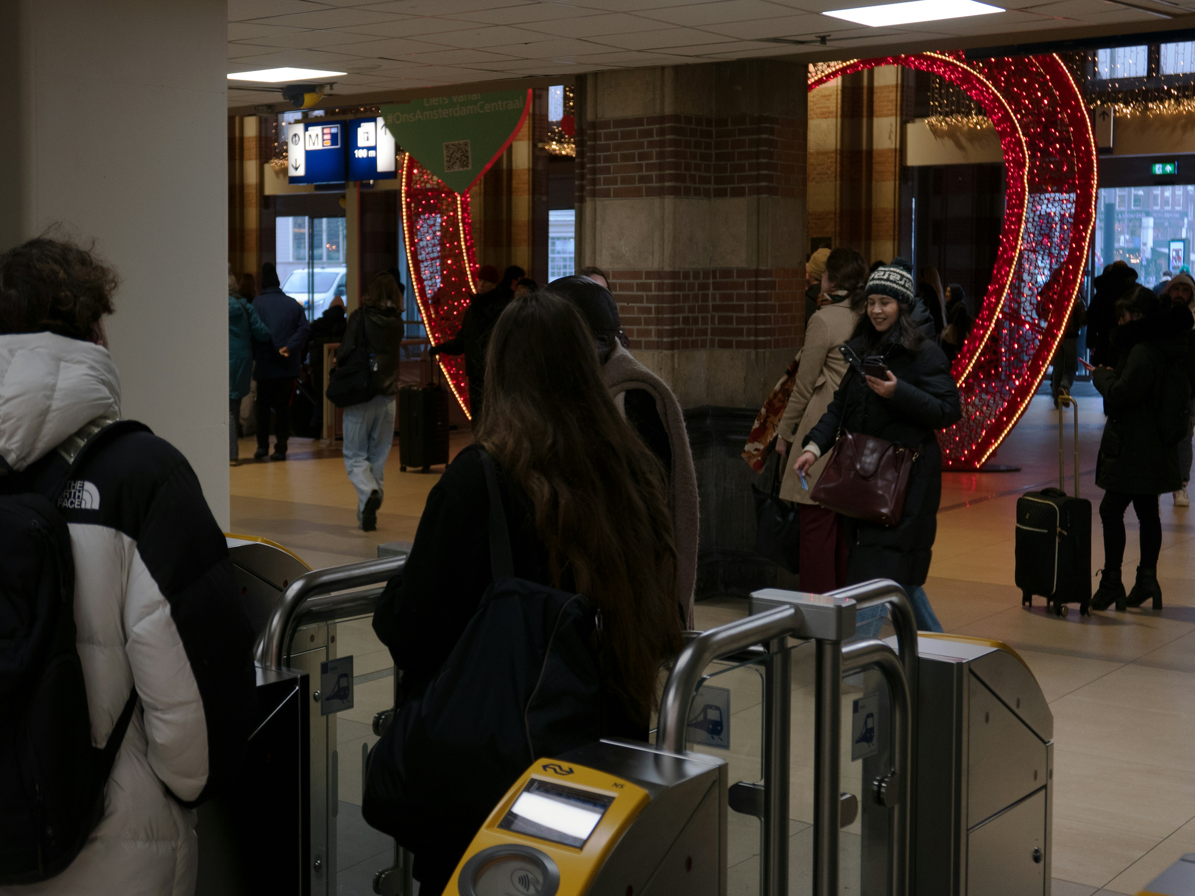 People at a train station with a large heart decoration