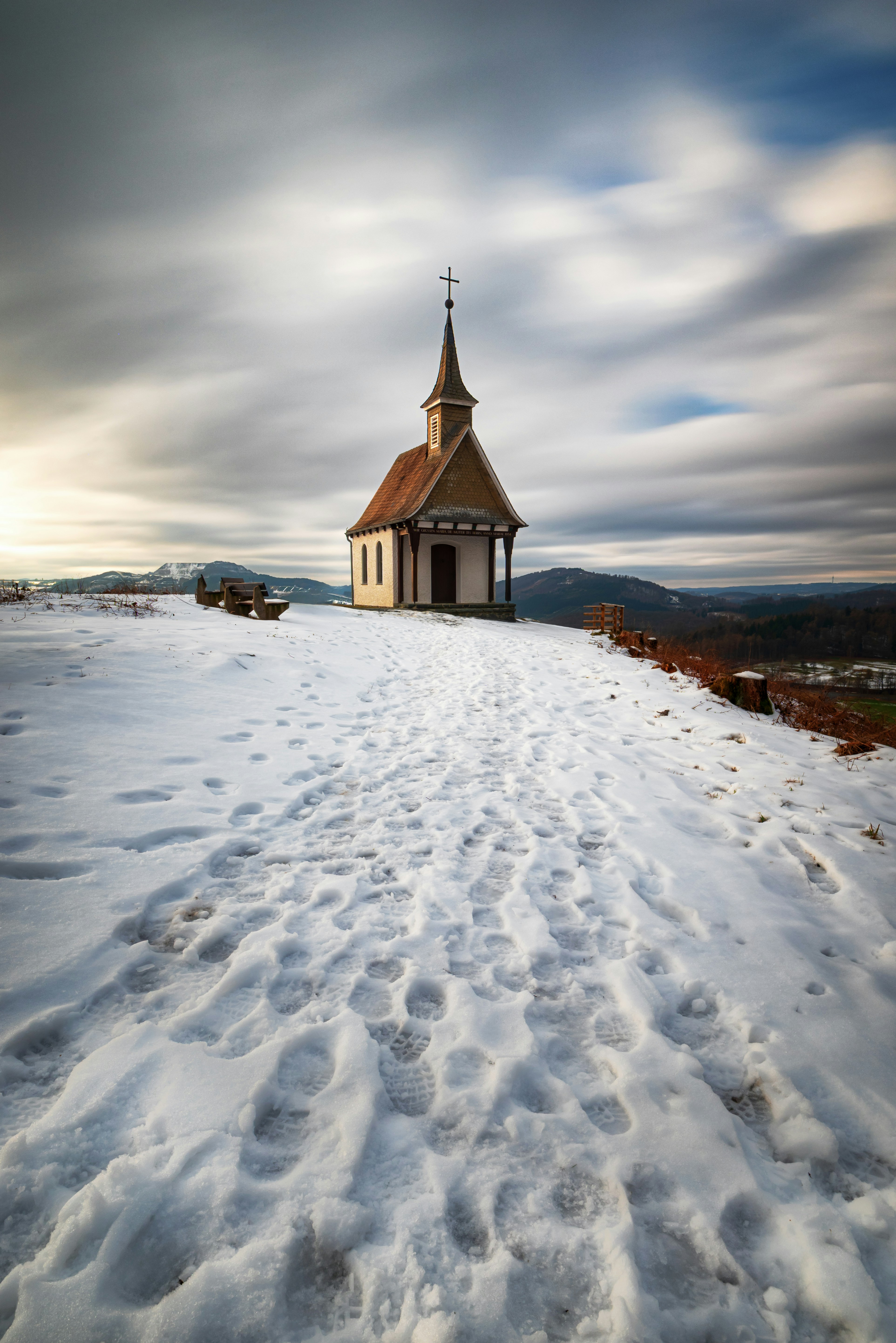 Kleine Kapelle auf einem schneebedeckten Hügel mit bewölktem Himmel