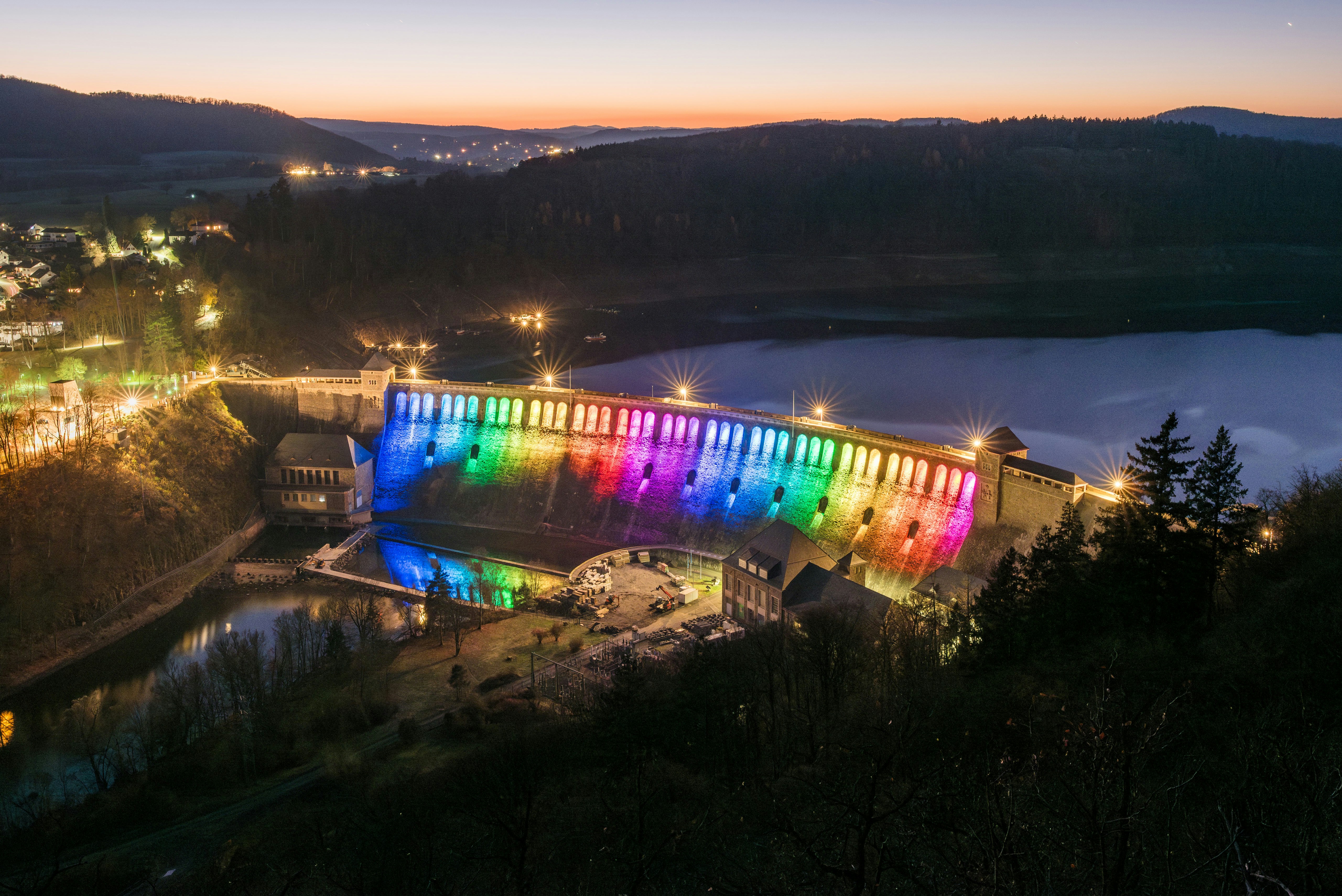 Dam illuminated with rainbow lights at dusk