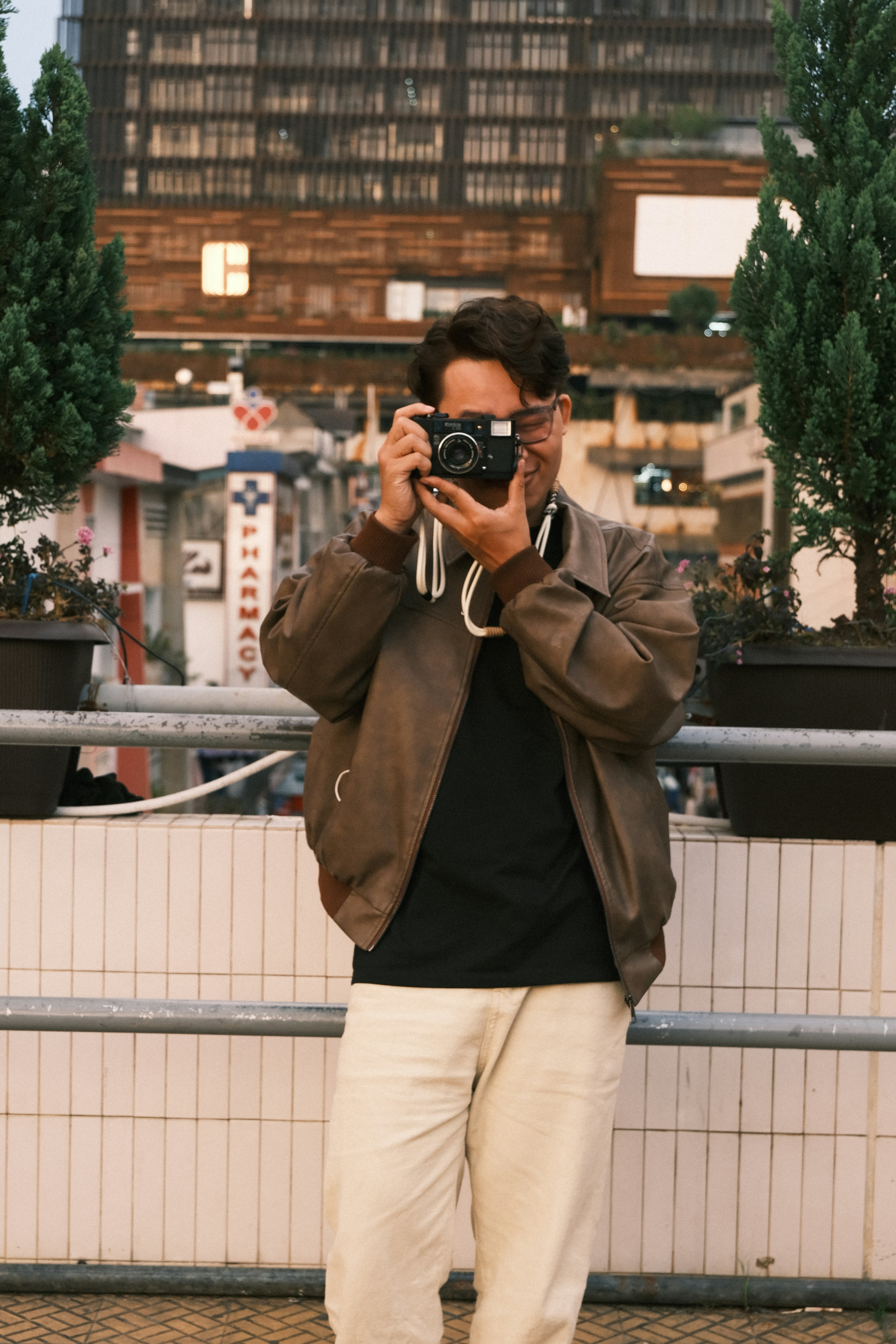Man in brown jacket taking a picture with vintage camera.