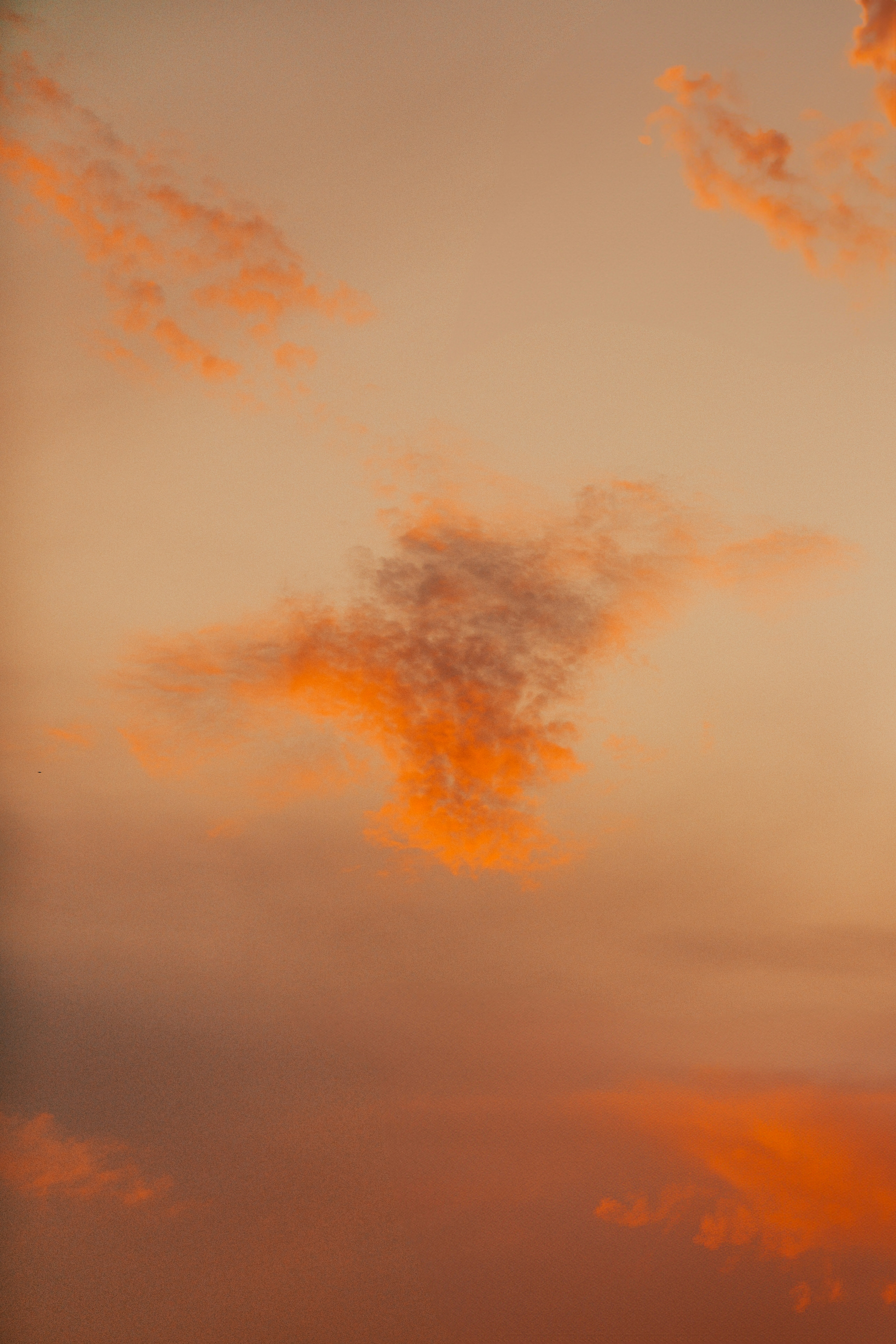 Orange clouds drift in a soft, hazy sky.