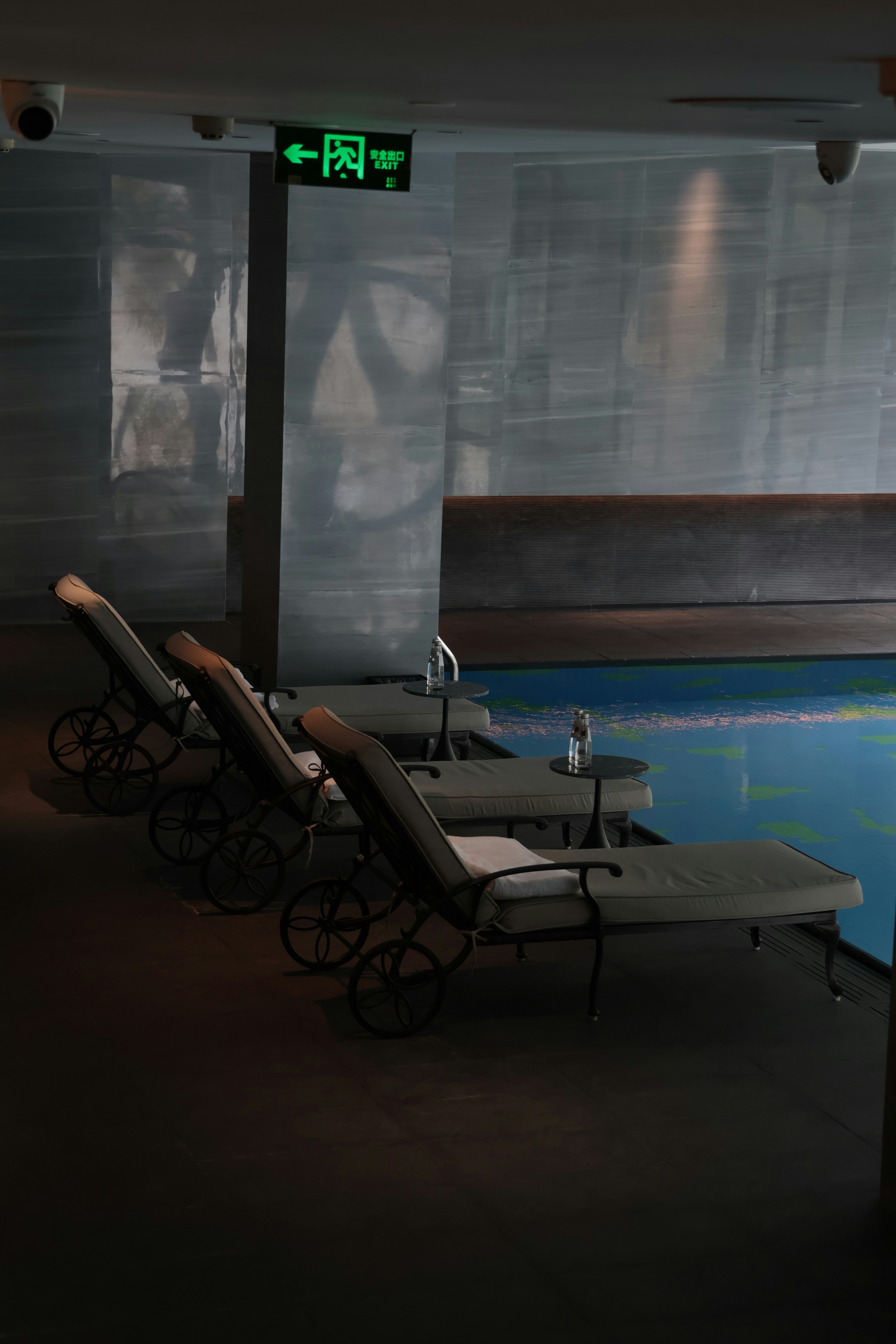 Three lounge chairs by a swimming pool.