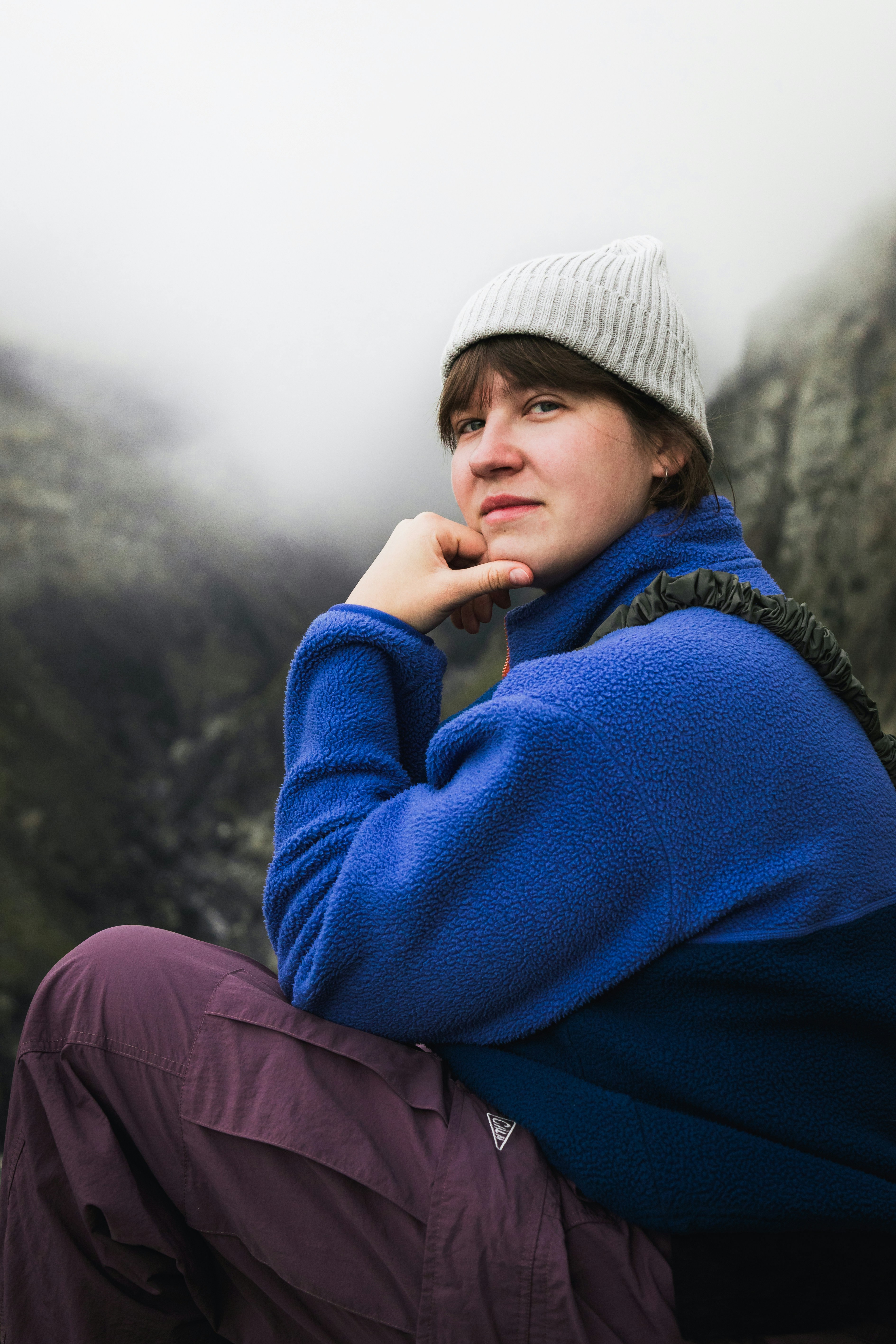 Young woman in beanie and blue jacket looks thoughtfully