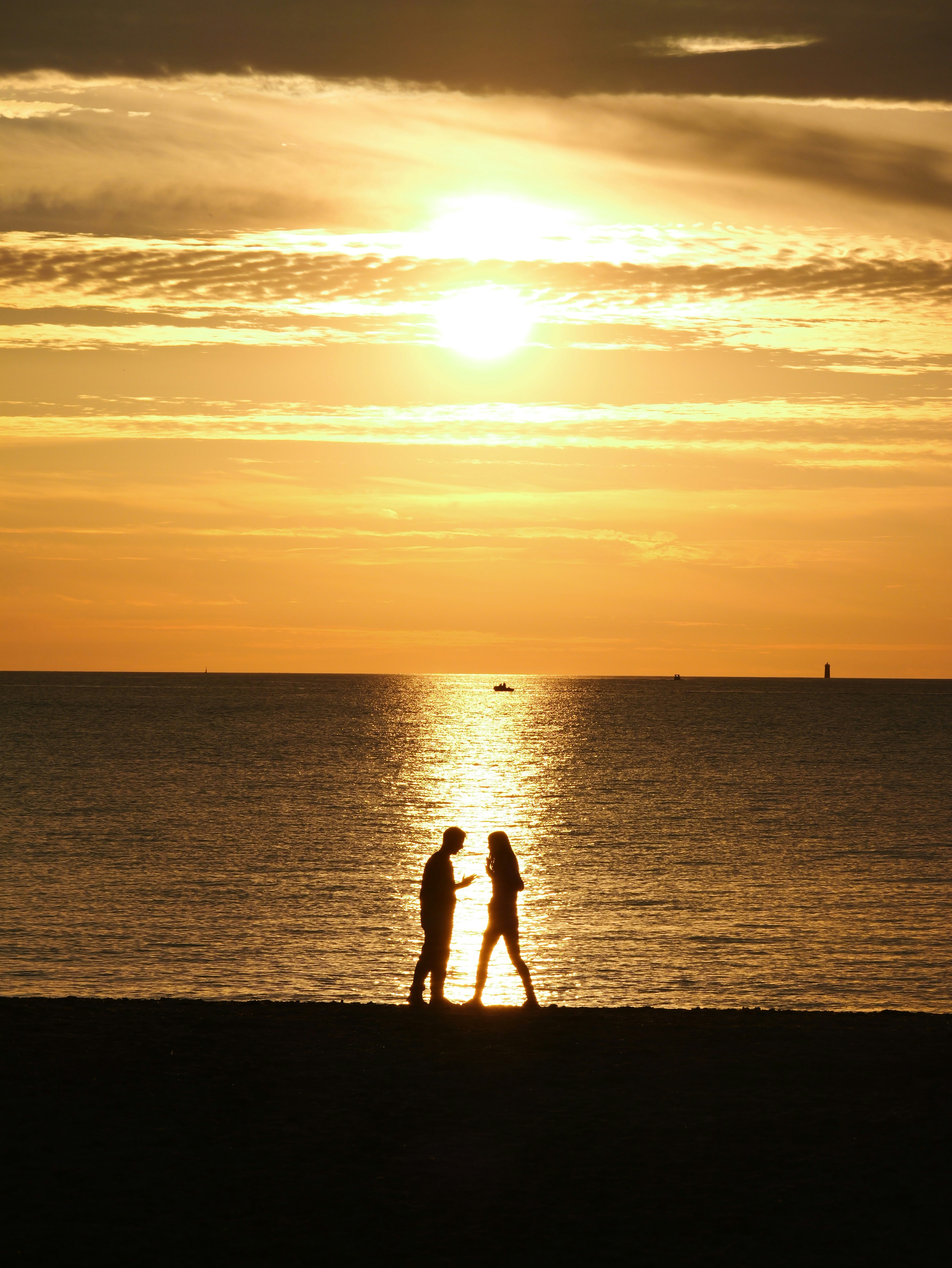 Pareja recortada contra un vibrante atardecer de playa