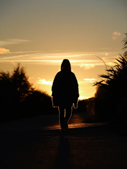 Silhouette of a person walking at sunset