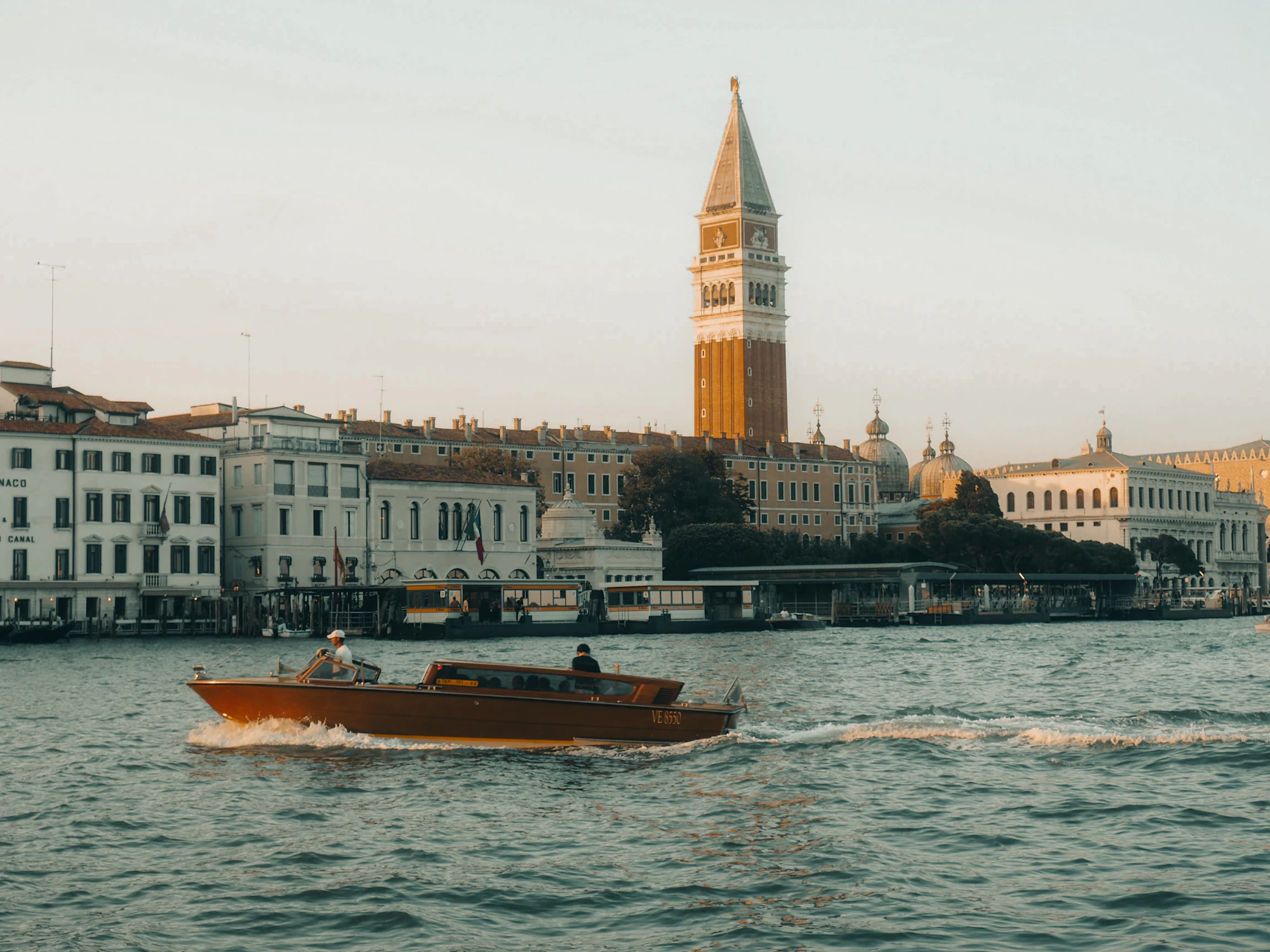 A boat travels on a canal in front of buildings