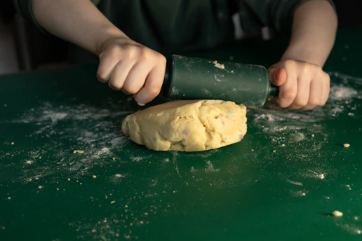 Child rolling out dough with a rolling pin.